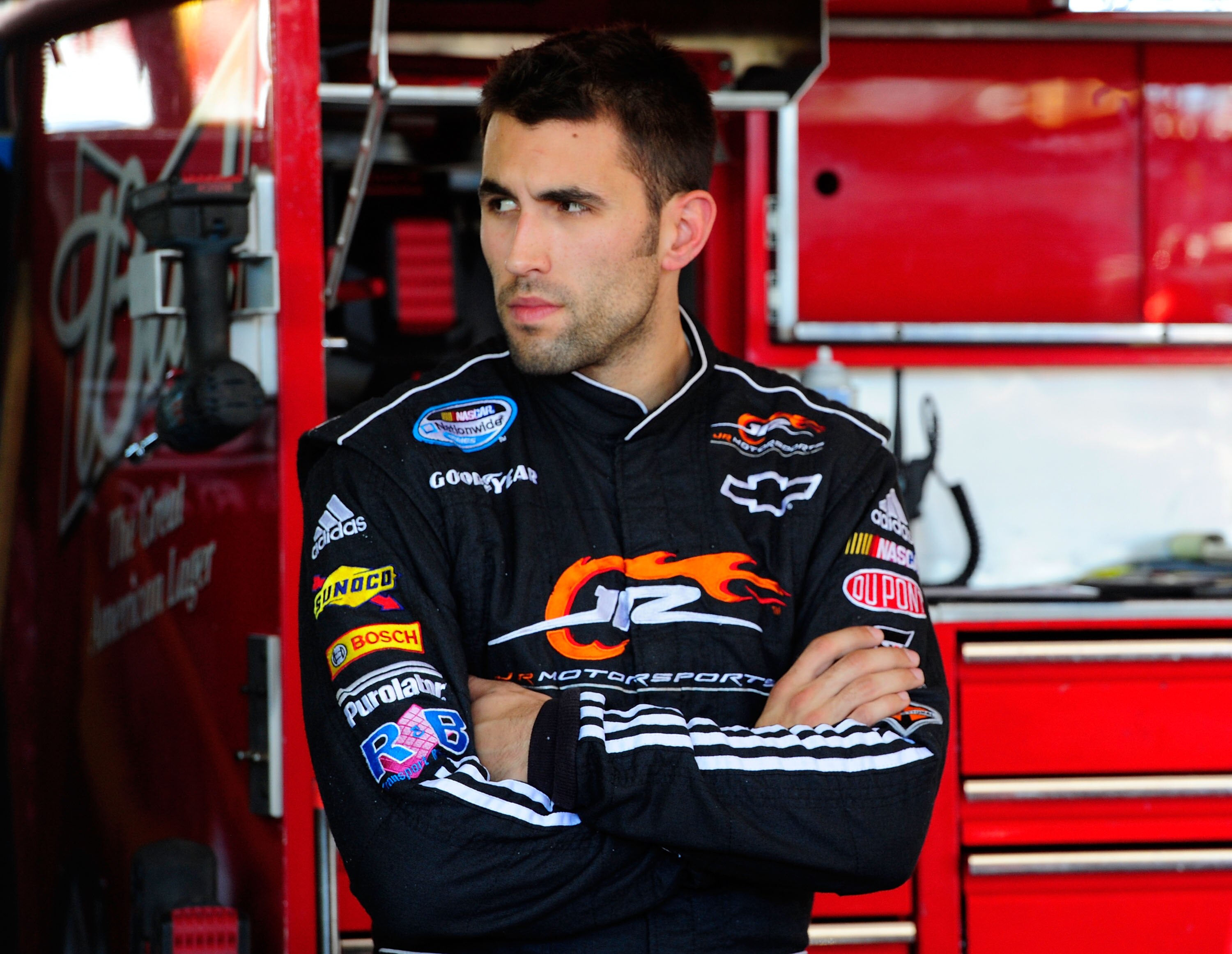 AVONDALE, AZ - NOVEMBER 12:  Aric Almirola, driver of the #9 Budweiser Ford, stands in the garage during practice for the NASCAR Sprint Cup Series Kobalt Tools 500 at Phoenix International Raceway on November 12, 2010 in Avondale, Arizona.  (Photo by Robe
