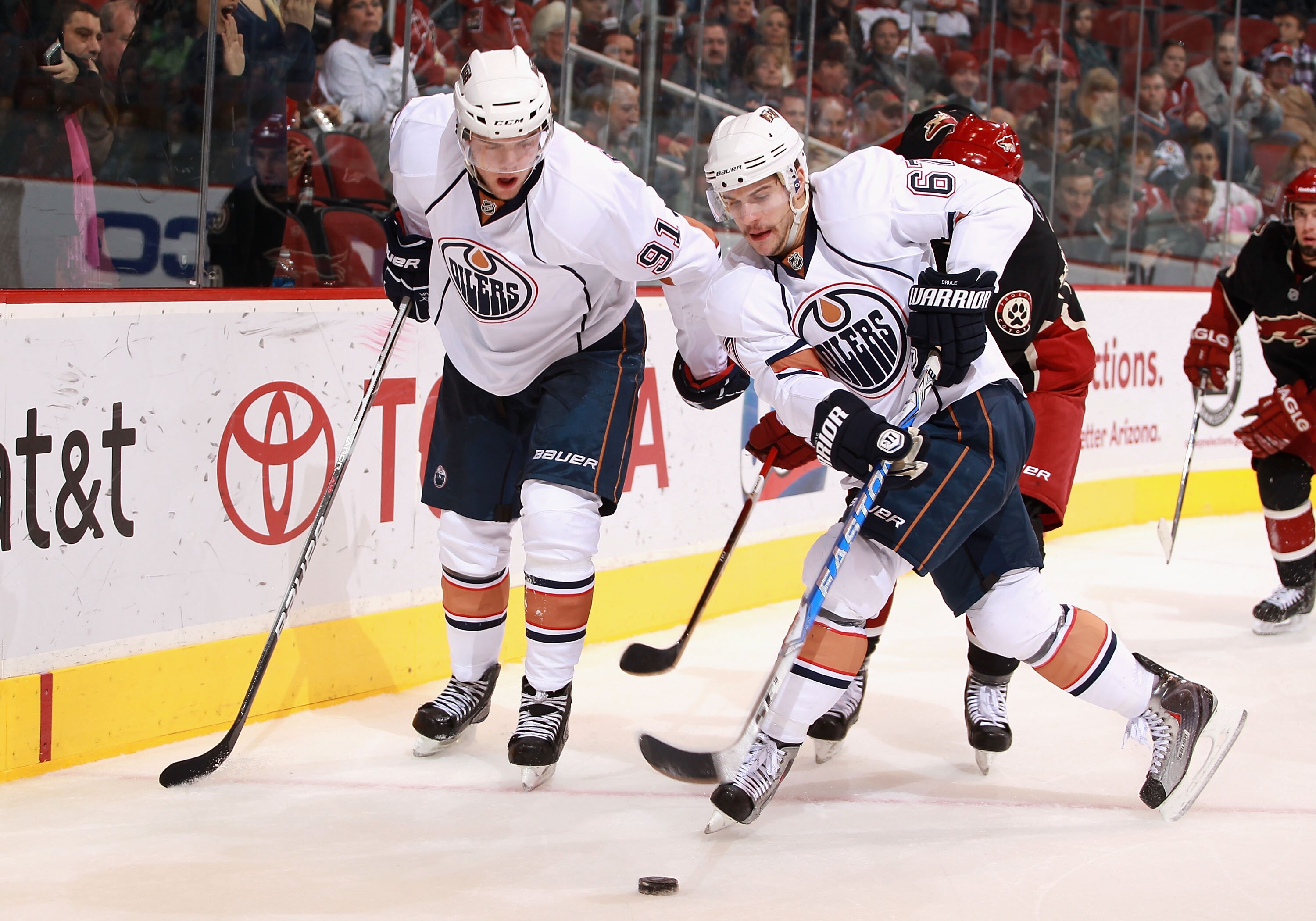 GLENDALE, AZ - NOVEMBER 23:  Gilbert Brule #67 of the Edmonton Oilers battles for a loose puck alongside teammate Magnus Paajarvi #91 during the NHL game against the Phoenix Coyotes at Jobing.com Arena on November 23, 2010 in Glendale, Arizona.  The Coyot