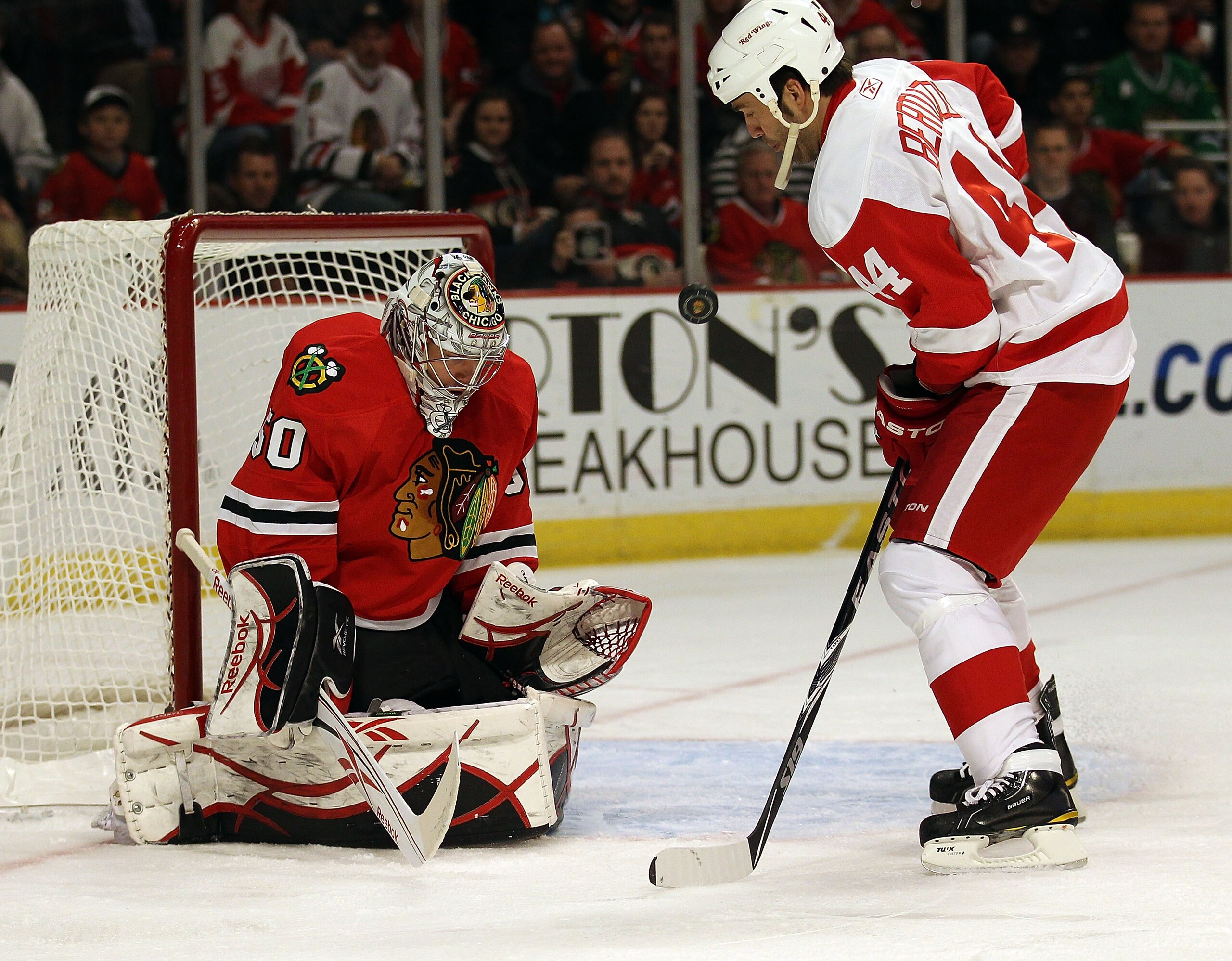 CHICAGO, IL - DECEMBER 17: Corey Crawford #50 of the Chicago Blackhawks makes a save and flips the puck in the air in front of Todd Bertuzzi #44 of the Detroit Red Wings at the United Center on December 17, 2010 in Chicago, Illinois. The Blackawks defeate