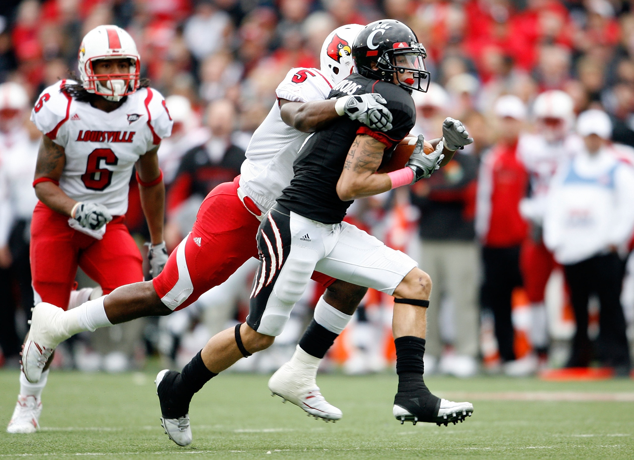 CINCINNATI - OCTOBER 24:  DJ Woods # 3 of the Cincinnati Bearcats runs with the ball while defended by Brandon Heath #5 of the Louisville Cardinals during the Big East Conference game at Nippert Stadium on October 24, 2009 in Cincinnati, Ohio.  (Photo by