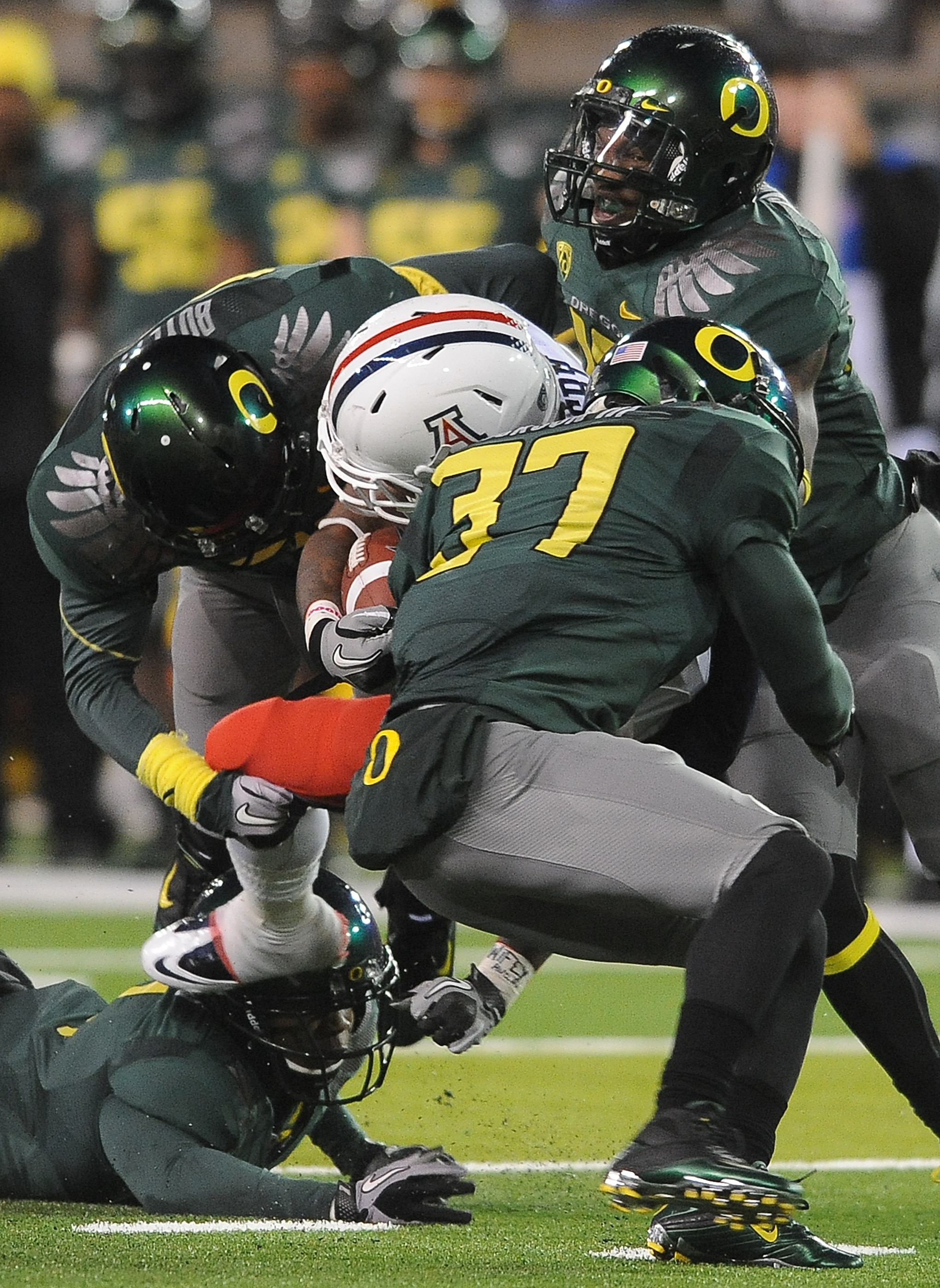 EUGENE, OR - NOVEMBER 26: Running back Nic Grigsby #5 of the Arizona Wildcats is tackled by cornerback Talmadge Jackson III #37 and safety John Boyett #20 of the Oregon Ducks in the fourth quarter of the game at Autzen Stadium on November 26, 2010 in Euge
