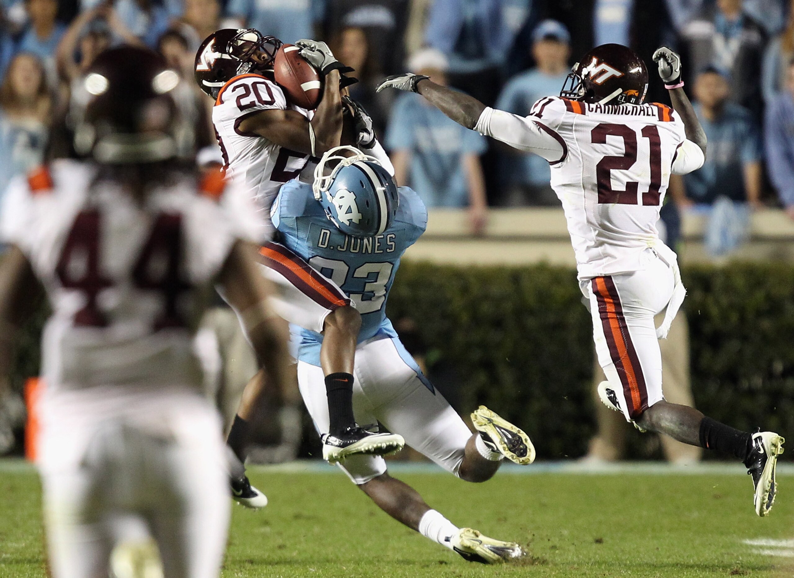 CHAPEL HILL, NC - NOVEMBER 13:  Jayron Hosley #20 of the Virginia Tech Hokies makes an interception as teammate Rashad Carmichael #21 watches on with Dwight Jones #83 of the North Carolina Tar Heels during their game at Kenan Stadium on November 13, 2010