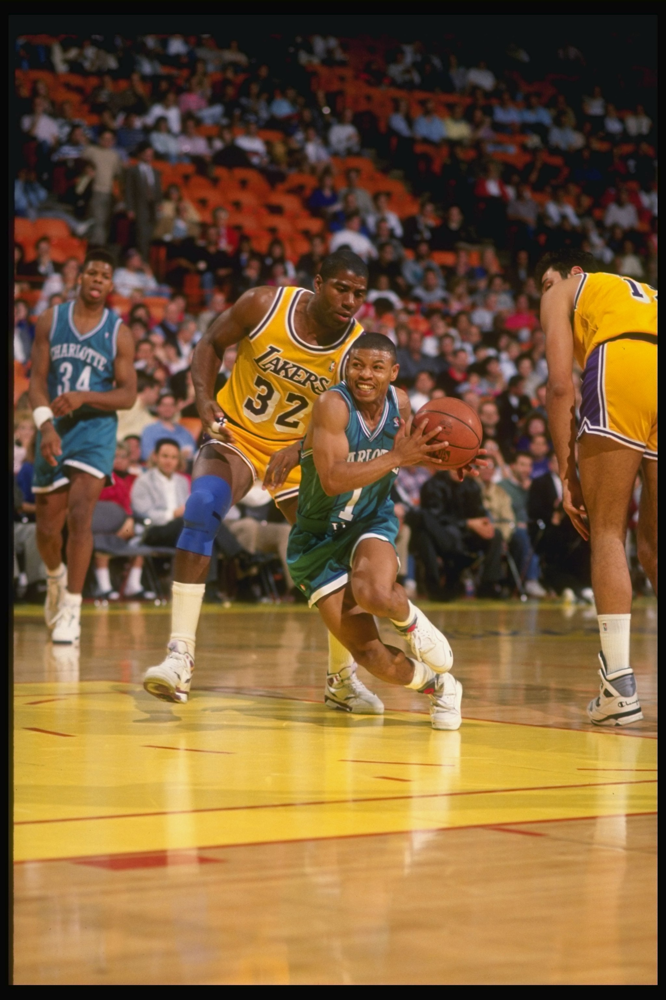 1990-1991:  Guard Tyrone (Muggsy) Bogues of the Charlotte Hornets (center) keeps the ball away from guard Magic Johnson of the Los Angeles Lakers (left) during a game at the Great Western Forum in Inglewood, California. Mandatory Credit: Ken Levine  /Alls