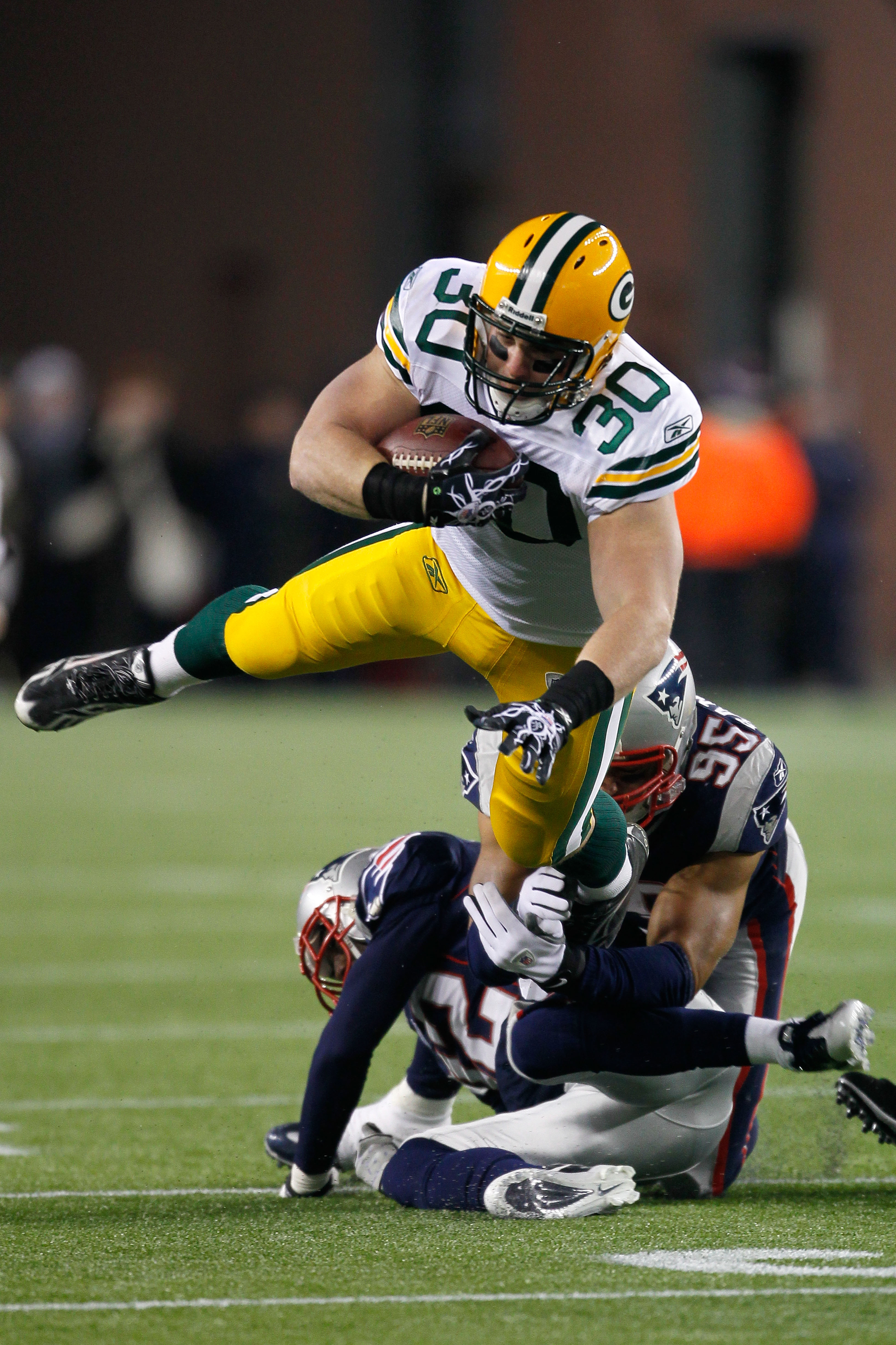 FOXBORO, MA - DECEMBER 19:  Running back John Kuhn #30 of the Green Bay Packers is tackled by linebacker Tully Banta-Cain #95 and cornerback Devin McCourty #32 of the New England Patriots during the first quarter of the game at Gillette Stadium on Decembe