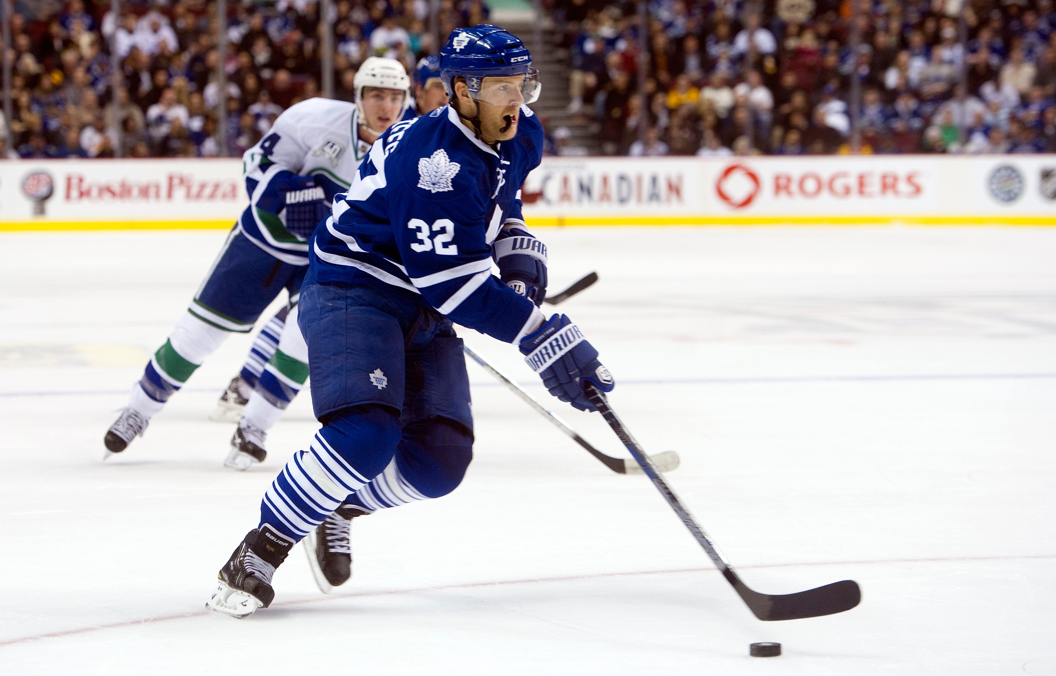 VANCOUVER, CANADA - DECEMBER 18: Kris Versteeg #32 of the Toronto Maple Leafs drives to the net while Alexandre Burrows #14 of the Vancouver Canucks watches in the background during the first period in NHL action on December 18, 2010 at Rogers Arena in Va