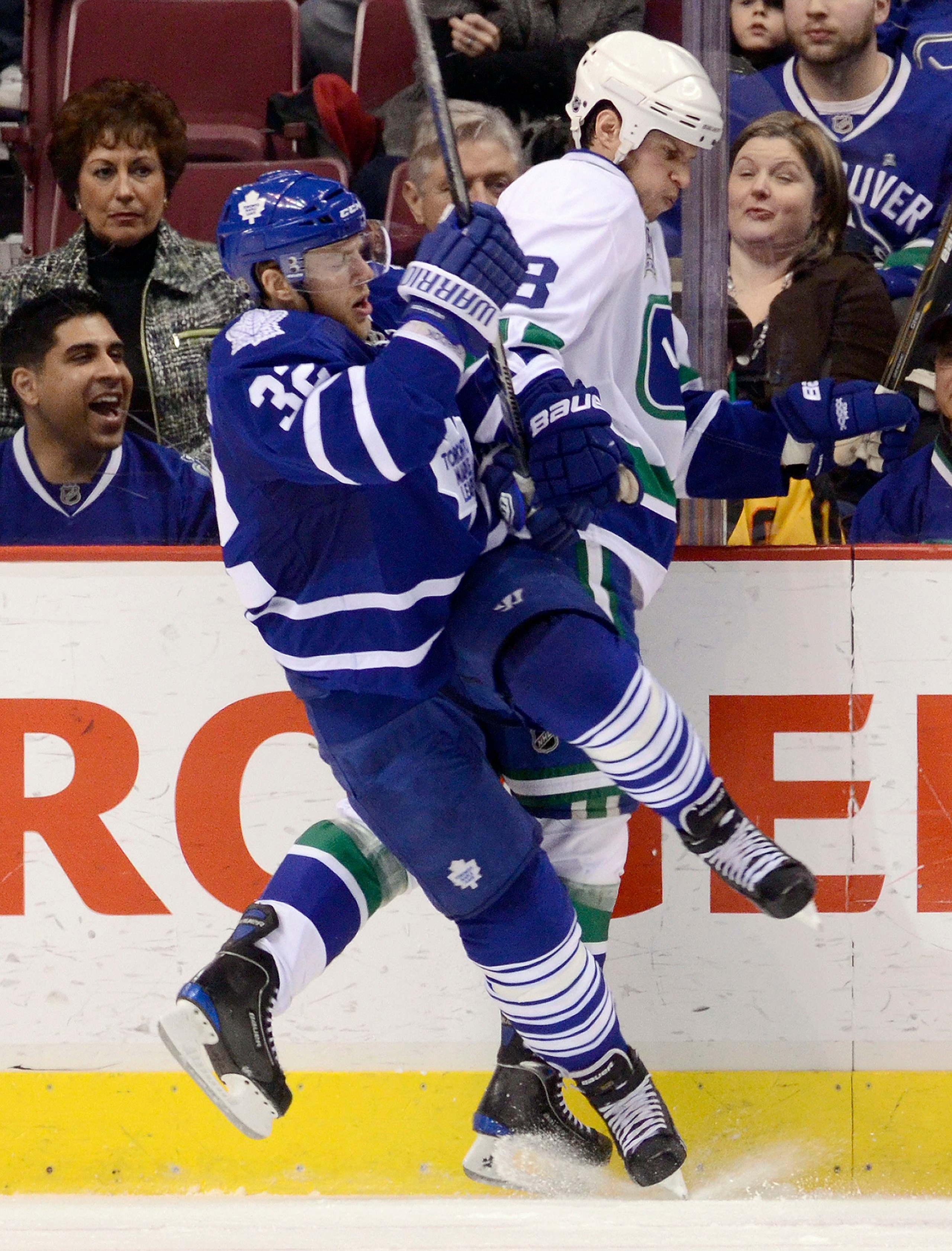 VANCOUVER, CANADA - DECEMBER 18: Kevin Bieksa #3 of the Vancouver Canucks and Kris Versteeg #32 of the Toronto Maple Leafs get tangled up along the side boards during the second period in NHL action on December 18, 2010 at Rogers Arena in Vancouver, BC, C