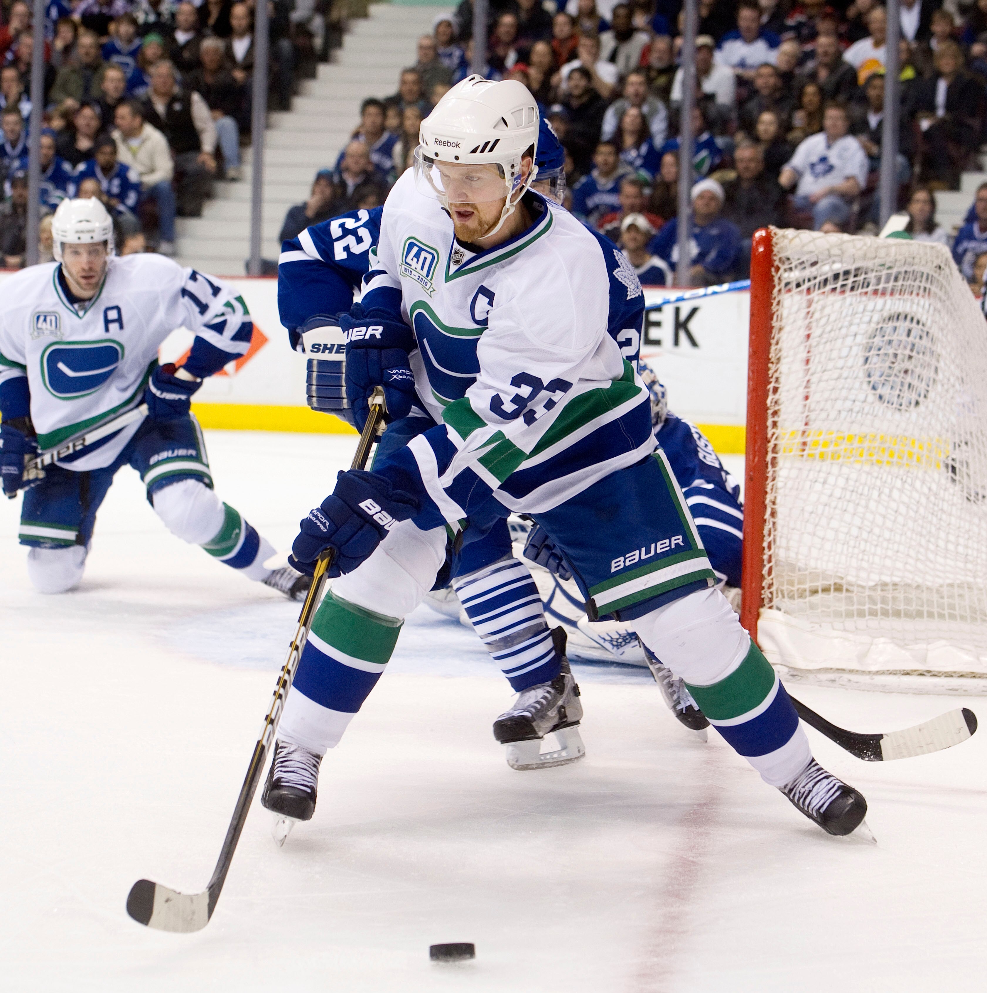 VANCOUVER, CANADA - DECEMBER 18: Henrik Sedin #33 of the Vancouver Canucks fends of Francois Beauchemin #22 of the Toronto Maple Leafs to keep control of the puck during the second period in NHL action on December 18, 2010 at Rogers Arena in Vancouver, BC
