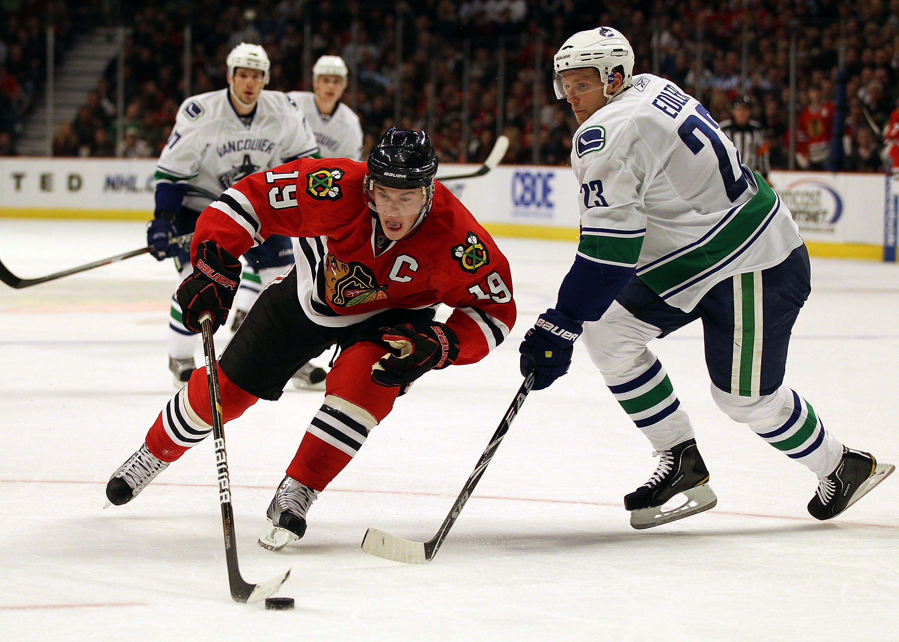 CHICAGO, IL - DECEMBER 03: Jonathan Toews #19 of the Chicago Blackhawks skates around Alexander Edler #23 of the Vancouver Canucks at the United Center on December 3, 2010 in Chicago, Illinois.  (Photo by Jonathan Daniel/Getty Images)