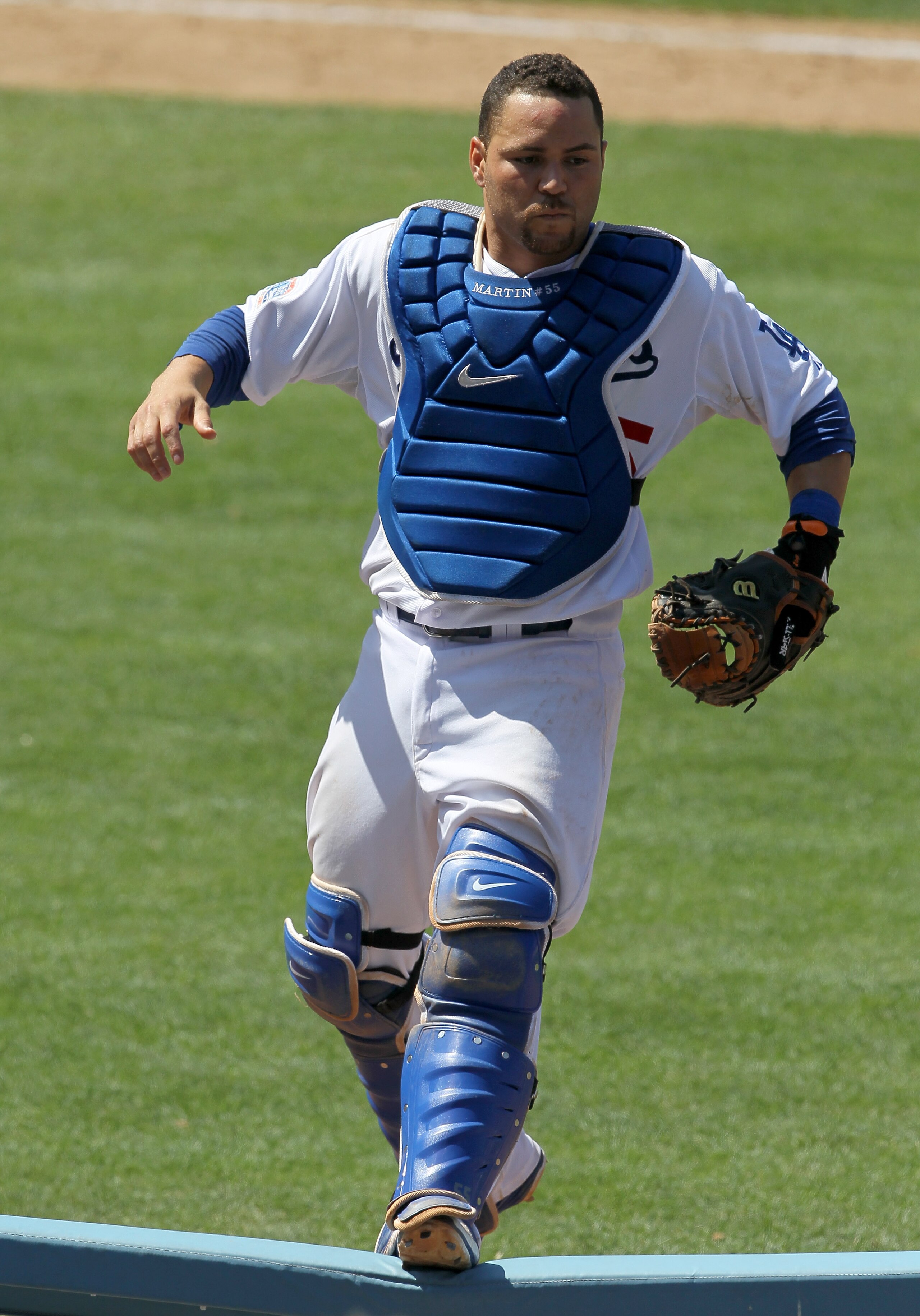 LOS ANGELES, CA - JULY 25:  Catcher Russell Martin #55 of the Los Angeles Dodgers jumps onto a rail beside the New York Mets dugouts as he pursues a pop foul ball that fell into the stands on July 25, 2010 at Dodger Stadium in Los Angeles, California.   T
