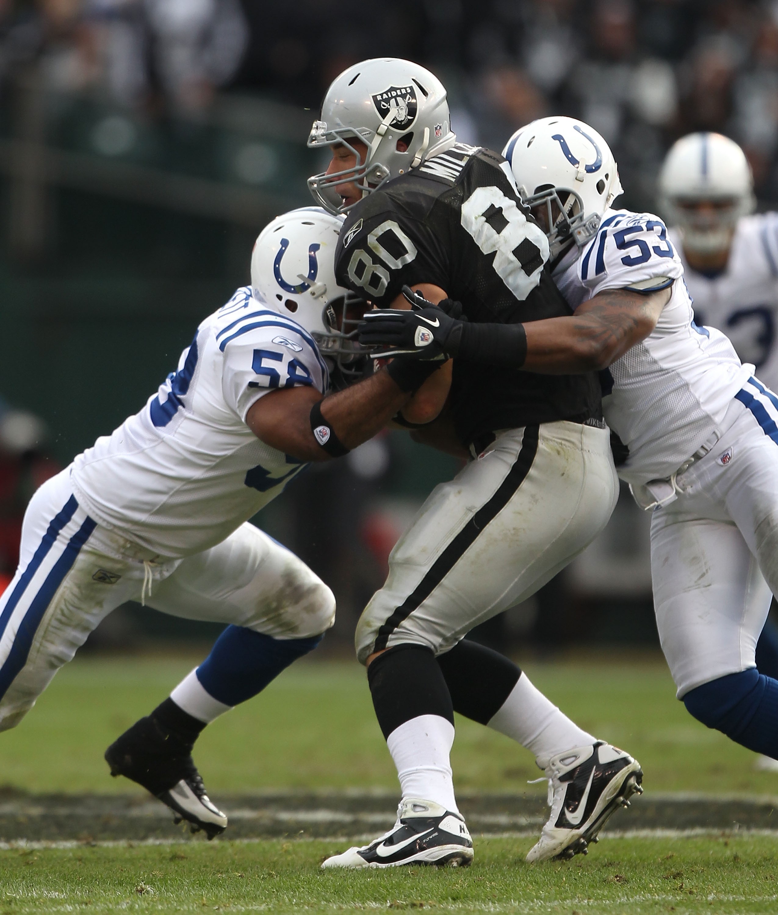 OAKLAND, CA - DECEMBER 26: Kavell Conner #53 and Tyjuan Hagler #56 of the Indianapolis Colts tackle Zach Miller #80 of the Oakland Raiders during an NFL game at Oakland-Alameda County Coliseum on December  26, 2010 in Oakland, California.  (Photo by Jed J