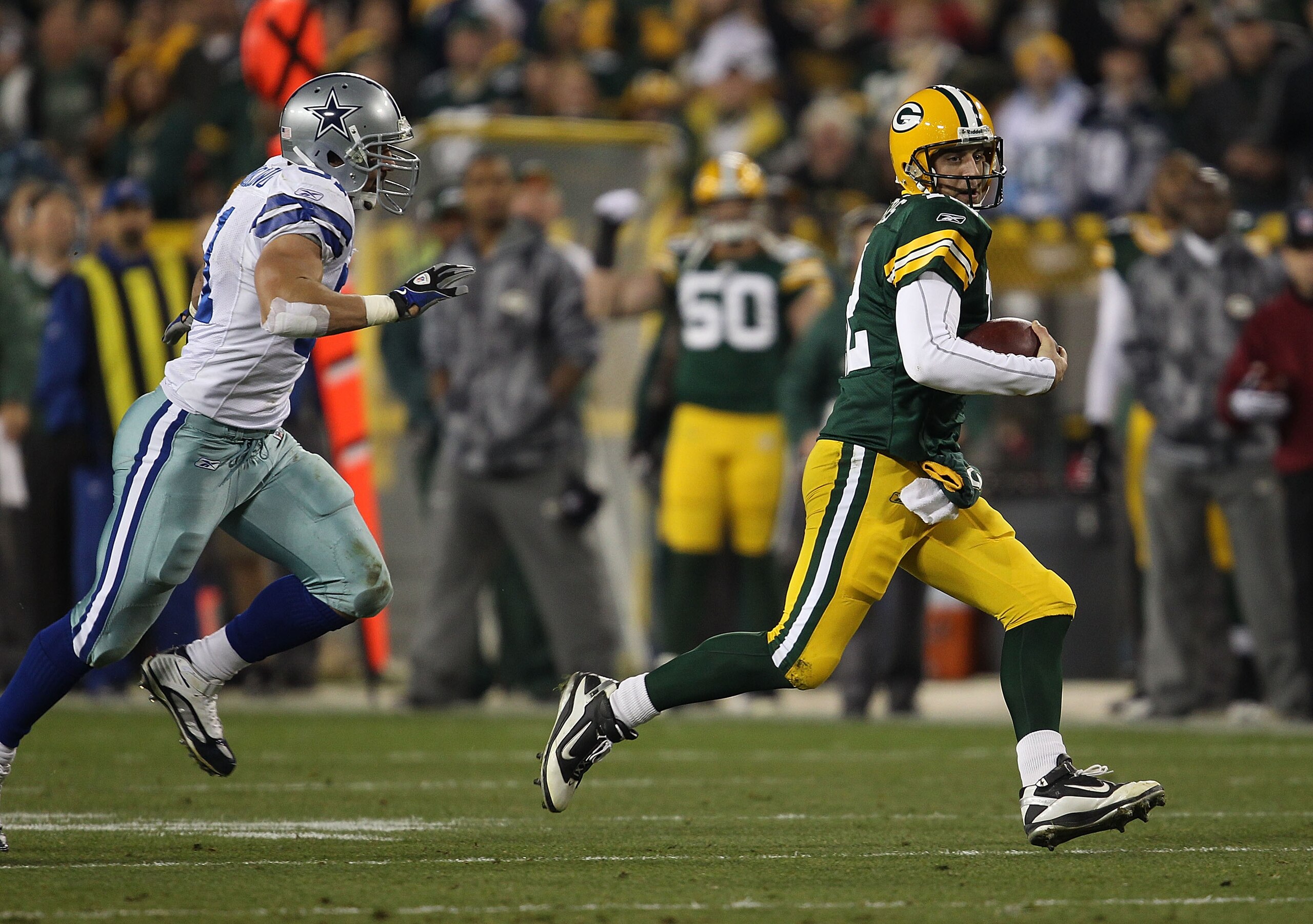 GREEN BAY, WI - NOVEMBER 07: Aaron Rodgers #12 of the Green Bay Packers runs for a first down pursued by Keith Brooking #51 of the Dallas Cowboys at Lambeau Field on November 7, 2010 in Green Bay, Wisconsin. The Packers defeated the Cowboys 45-7. (Photo GREEN BAY, WI - NOVEMBER 07: Aaron Rodgers #12 of the Green Bay Packers runs for a first down pursued by Keith Brooking #51 of the Dallas Cowboys at Lambeau Field on November 7, 2010 in Green Bay, Wisconsin. The Packers defeated the Cowboys 45-7. (Photo