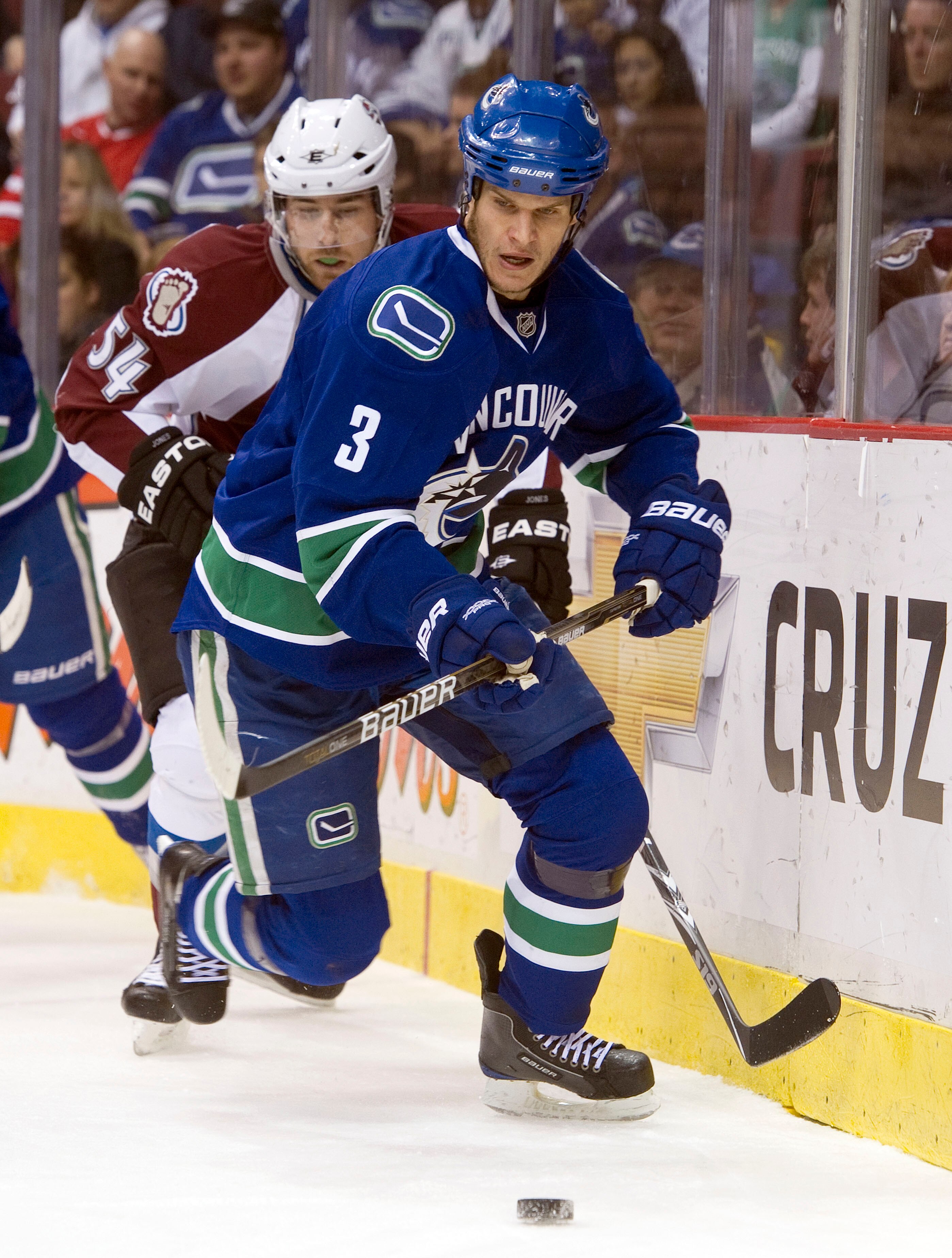 VANCOUVER, CANADA - NOVEMBER 24: Kevin Bieksa #3 of the Vancouver Canucks chases down a loose puck after hitting David Jones #54 of the Colorado Avalanche into the end boards during the first period in NHL action on November 24, 2010 at Rogers Arena in Va