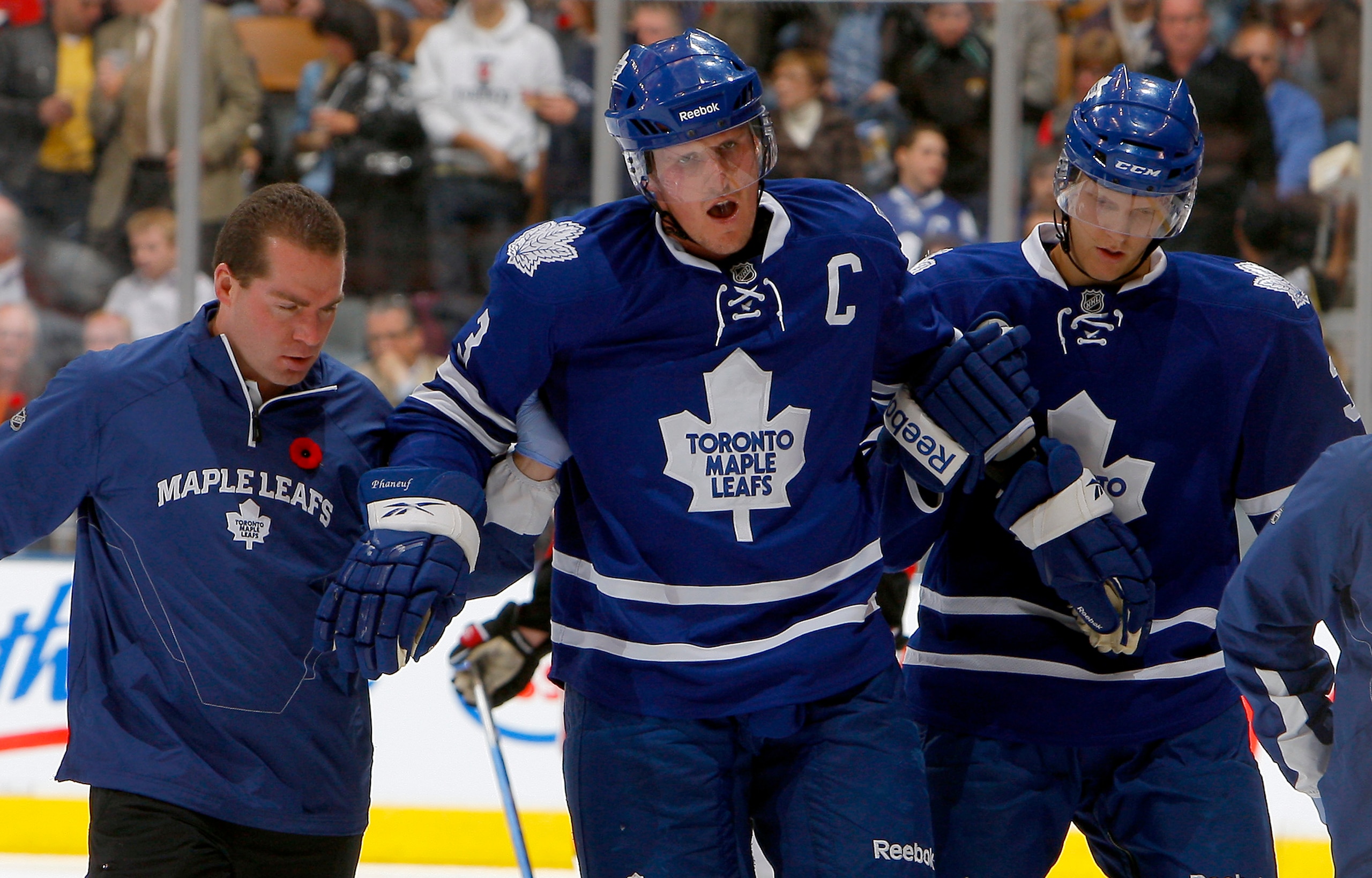 TORONTO - NOVEMBER 2:  Dion Phaneuf #3 of the Toronto Maple Leafs is taken off the ice by head athletic therapist  Andy Playter and Carl Gunnarsson #36 during NHL action against the Ottawa Senators at the Air Canada Centre November 2, 2010 in Toronto, Ont