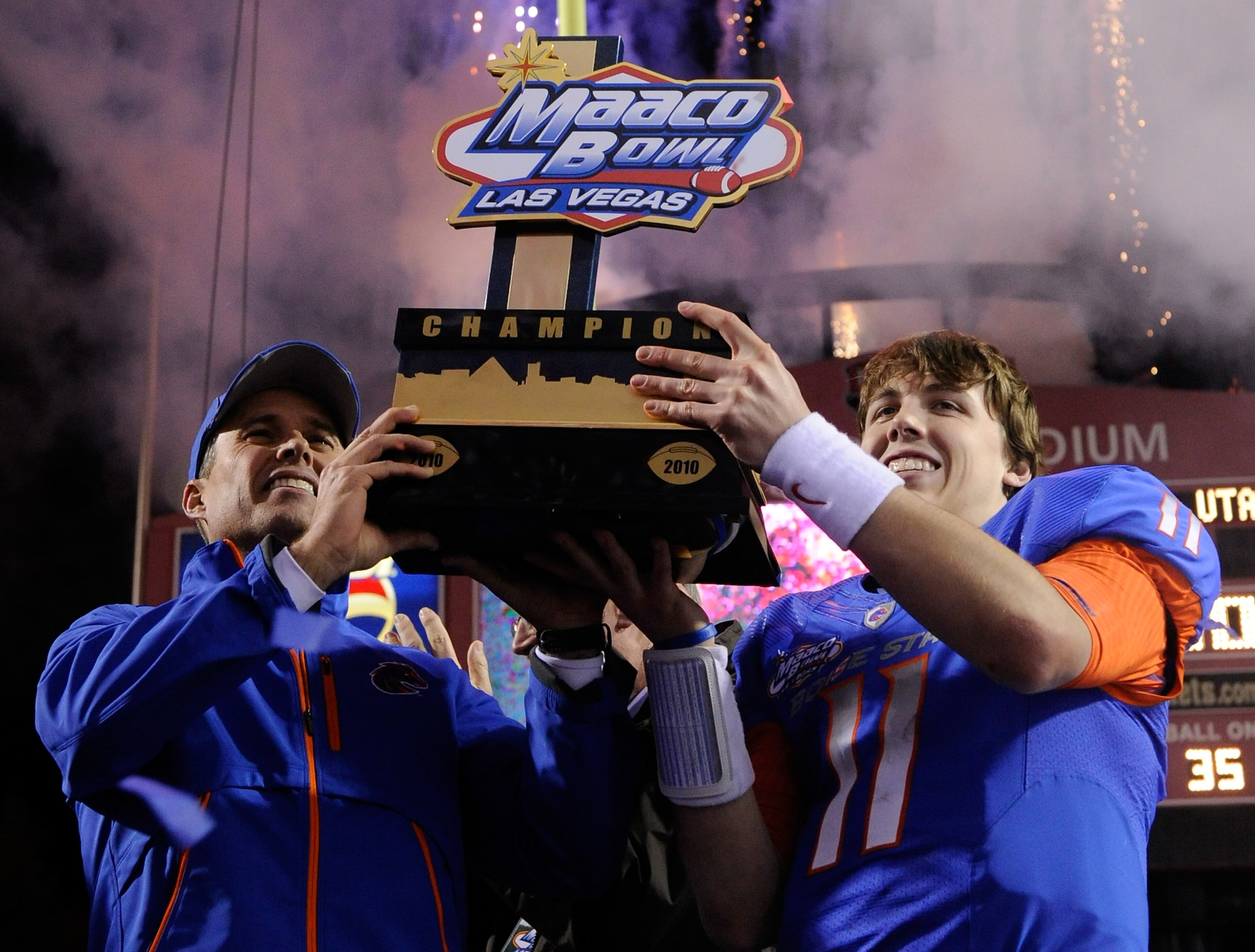 LAS VEGAS, NV - DECEMBER 22:  Head coach Chris Petersen (L) and quarterback Kellen Moore #11 of the Boise State Broncos hold up a trophy as they celebrate their 26-3 victory over the Utah Utes in the MAACO Bowl Las Vegas at Sam Boyd Stadium December 22, 2