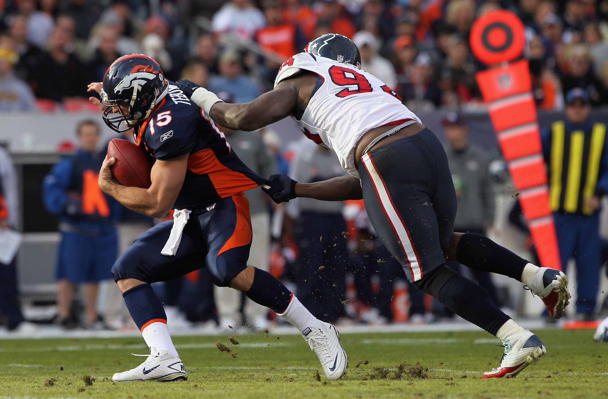 DENVER - DECEMBER 26:  Quarterback Tim Tebow #15 of the Denver Broncos eludes a sack attempt by defensive end Antonio Smith #94 of the Houston Texas at INVESCO Field at Mile High on December 26, 2010 in Denver, Colorado.  (Photo by Doug Pensinger/Getty Im
