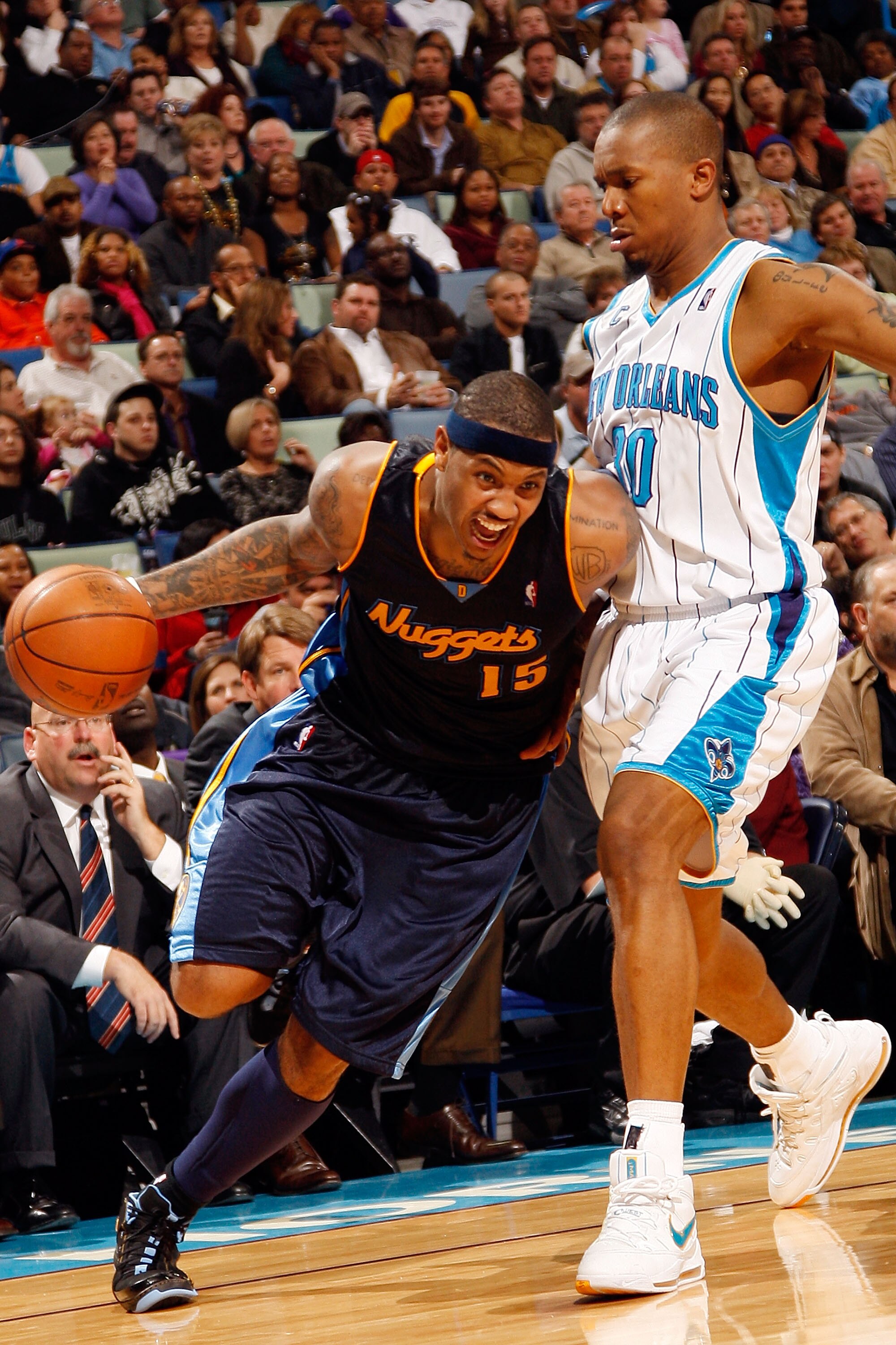 NEW ORLEANS - DECEMBER 18:  Carmelo Anthony #15 of the Denver Nuggets drives around David West #30 of the New Orleans Hornets at New Orleans Arena on December 18, 2009 in New Orleans, Louisiana.  The Hornets defeated the Nuggets 98-92.  NOTE TO USER: User
