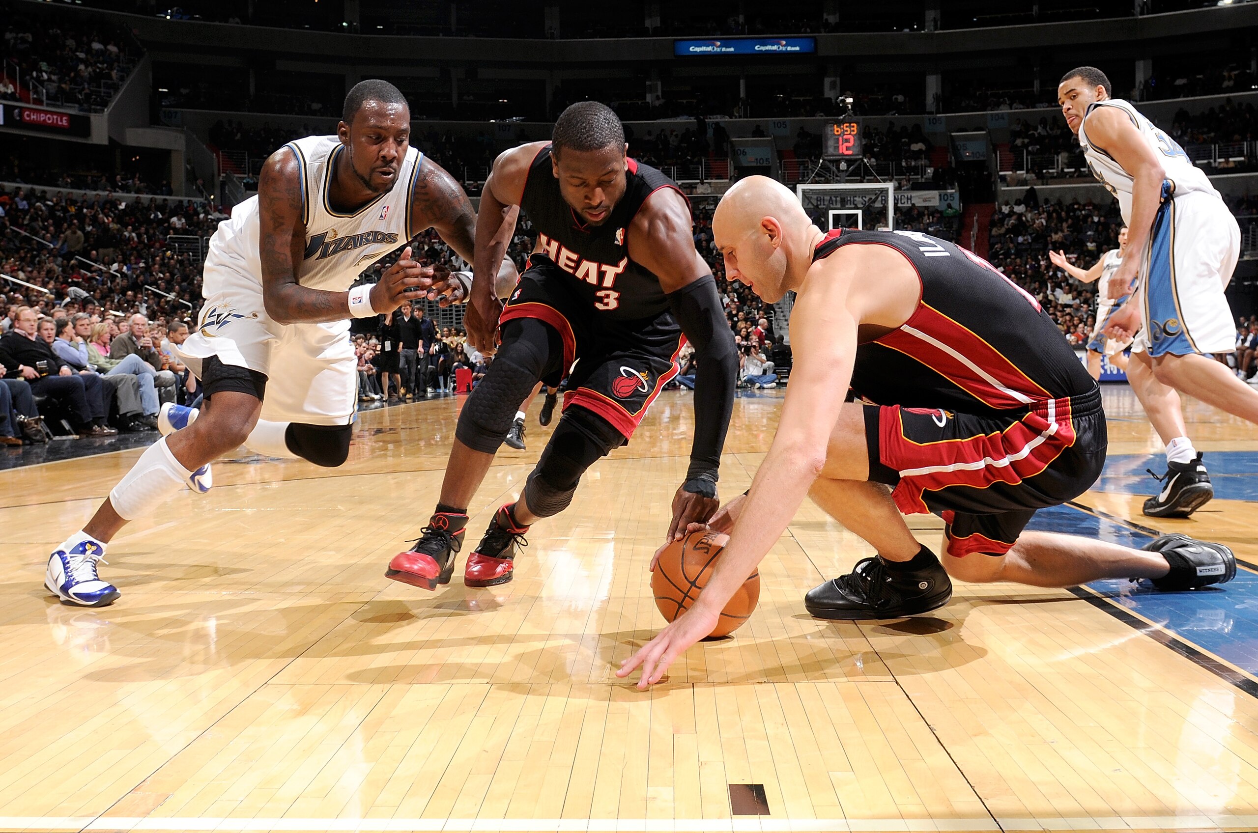 WASHINGTON - DECEMBER 18:  Zydrunas Ilgauskas #11 and Dwyane Wade #3 of the Miami Heat dive for a loose ball against Andray Blatche #7 of the Washington Wizards at the Verizon Center on December 18, 2010 in Washington, DC. NOTE TO USER: User expressly ack