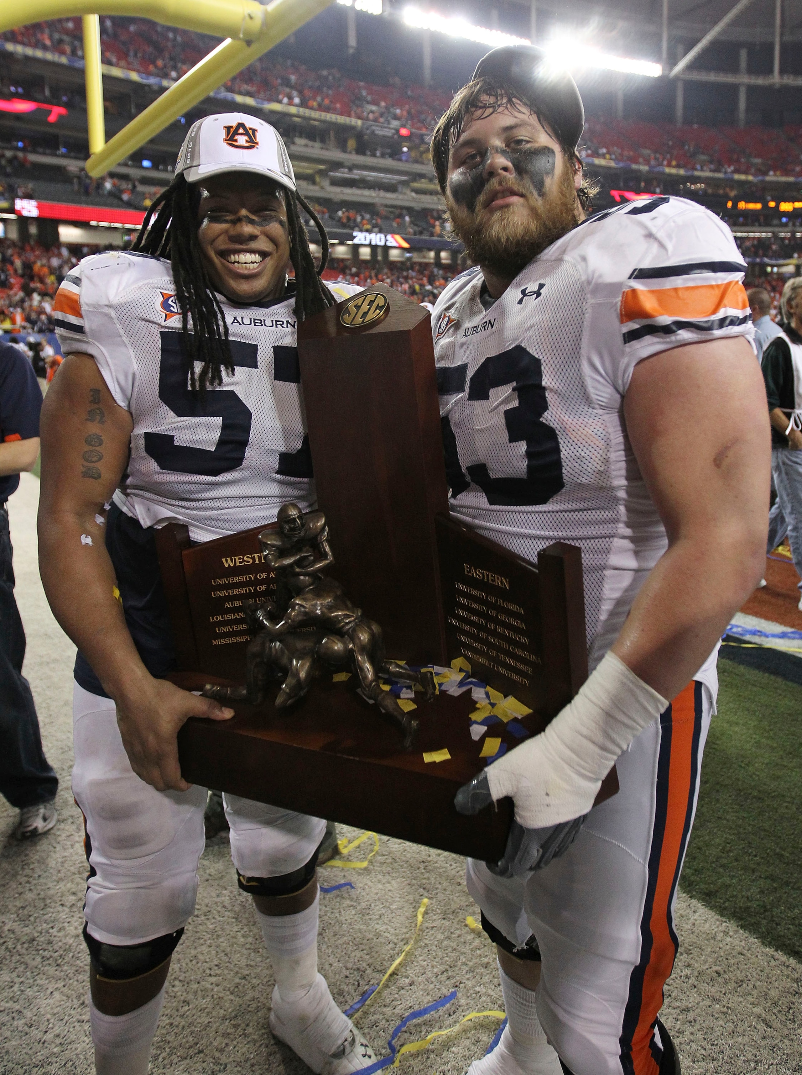ATLANTA - DECEMBER 4:  Lineman Bryon Isom #57 (left) and Bart Eddins #53 of the Auburn Tigers celebrate with the SEC Championship trophy after the 2010 SEC Championship against the South Carolina Gamecocks at Georgia Dome on December 4, 2010 in Atlanta, G