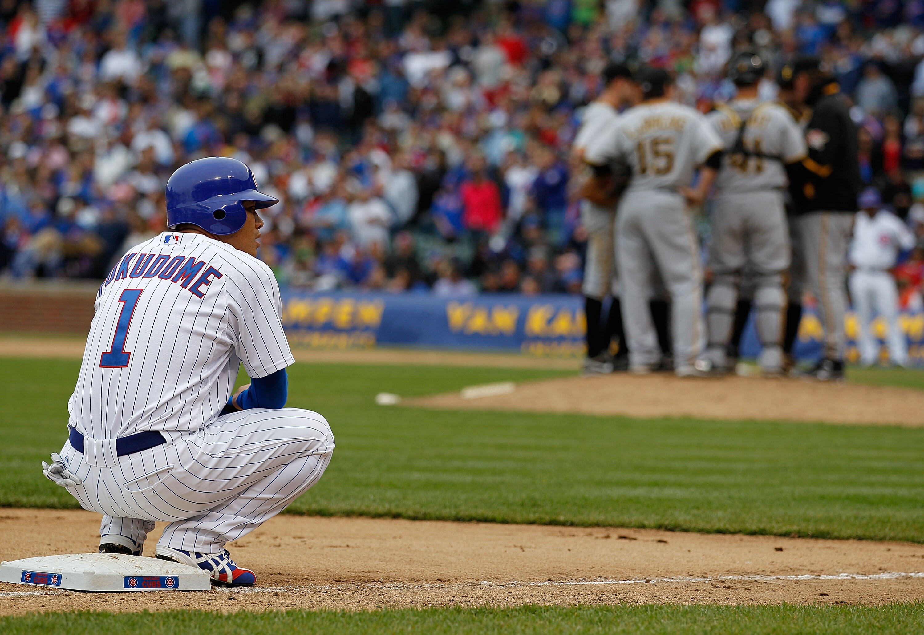 CHICAGO - MAY 15: Kosuke Fukudome #1 of the Chicago Cubs waits on third base after hitting a run-scoring triple in the 9th inning as members of the Pittsburgh Pirates plan strategy at the mound at Wrigley Field on May 15, 2010 in Chicago, Illinois. The Pi