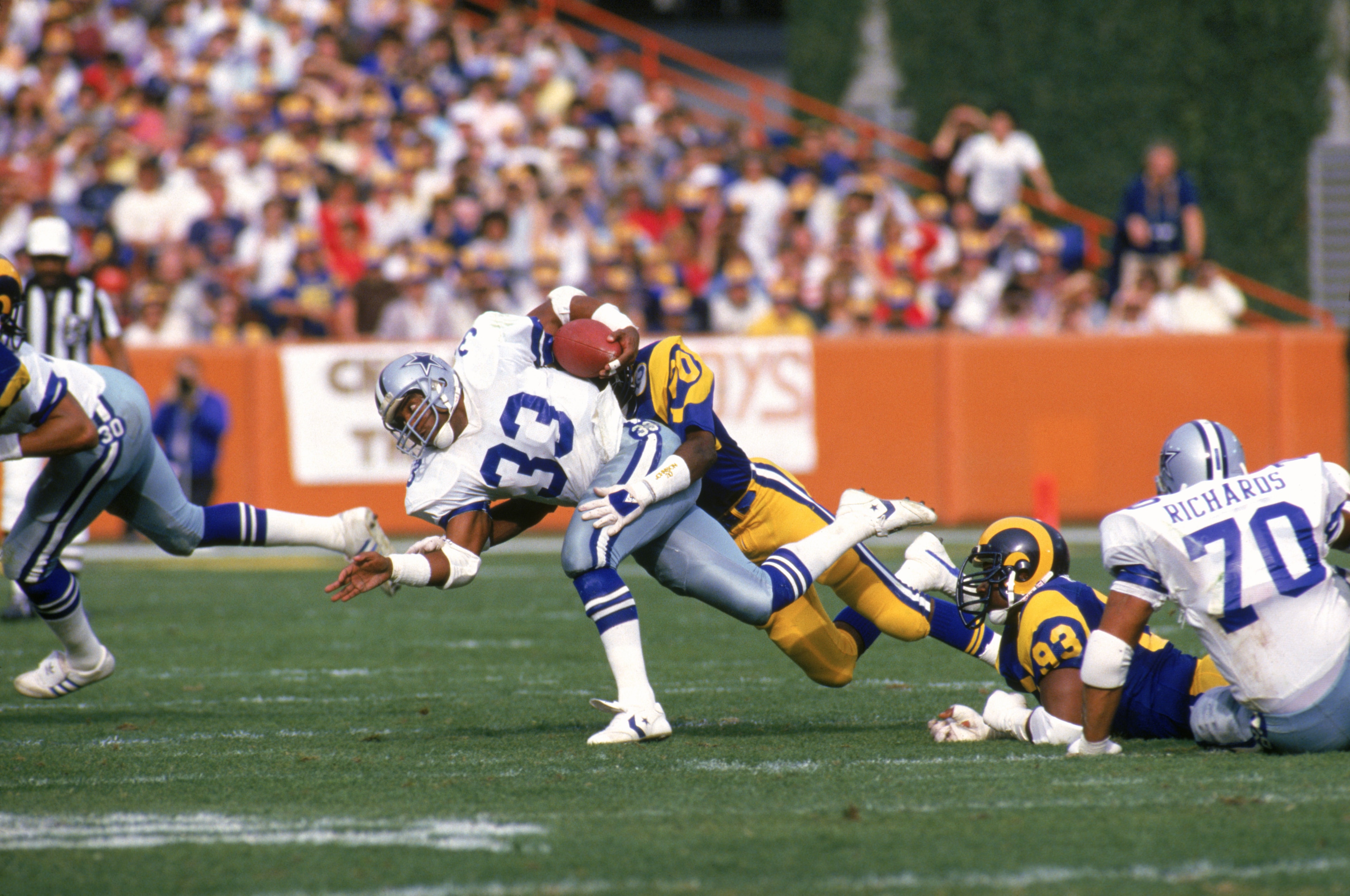 ANAHEIM, CA - JANUARY 4:  Running back Tony Dorsett #33 of the Dallas Cowboys gets tackled by defensive back Johnnie Johnson #20 of the Los Angeles Rams during a 1985 NFC Divisional Playoff game at Anaheim Stadium on January 4, 1996 in Anaheim, California