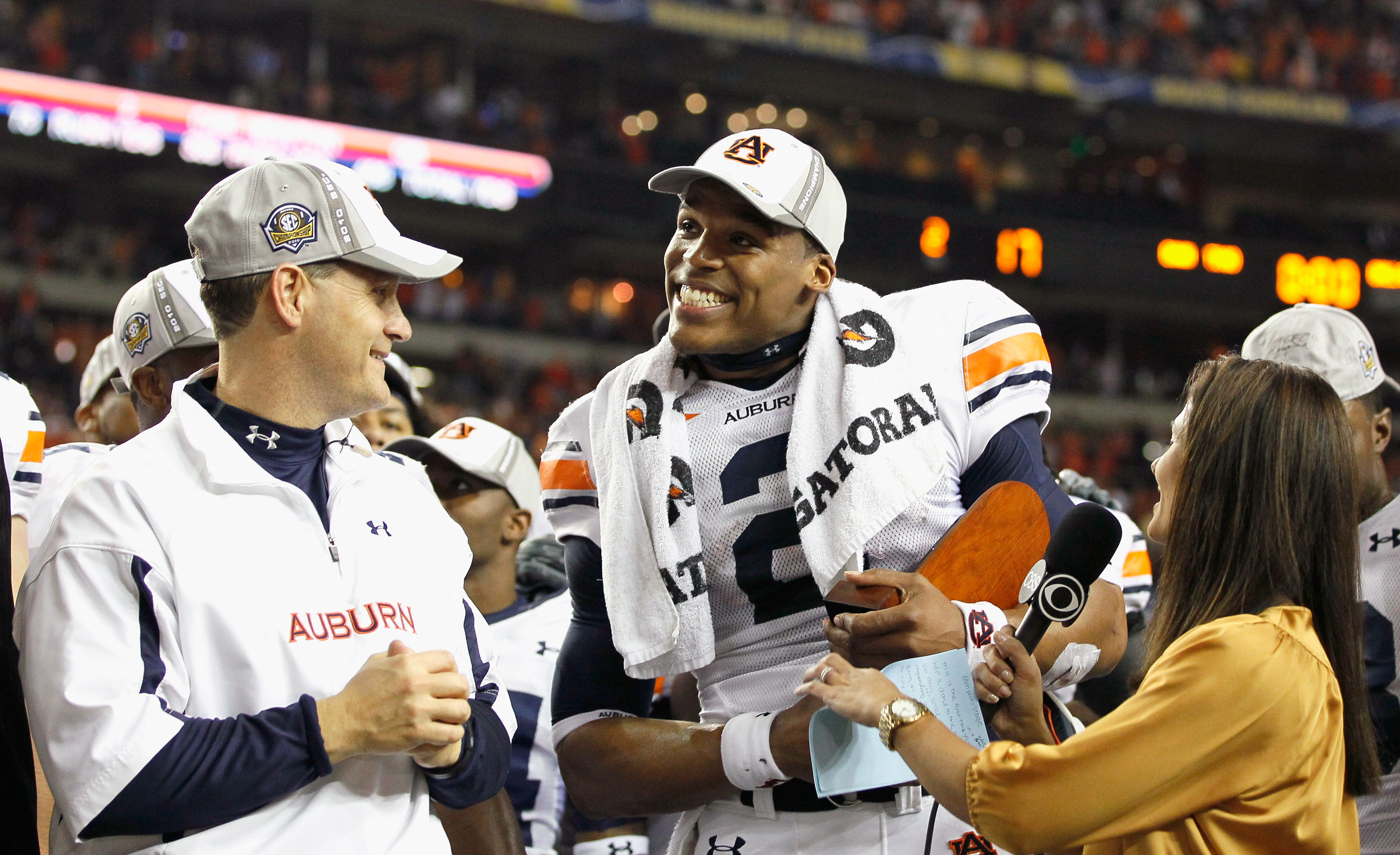 ATLANTA, GA - DECEMBER 04:  CBS sideline reporter Tracy Wolfson (R) and head coach Gene Chizik look on as quarterback Cam Newton #2 of the Auburn Tigers accepts the MVP trophy after their 56-17 win over the South Carolina Gamecocks during the 2010 SEC Cha