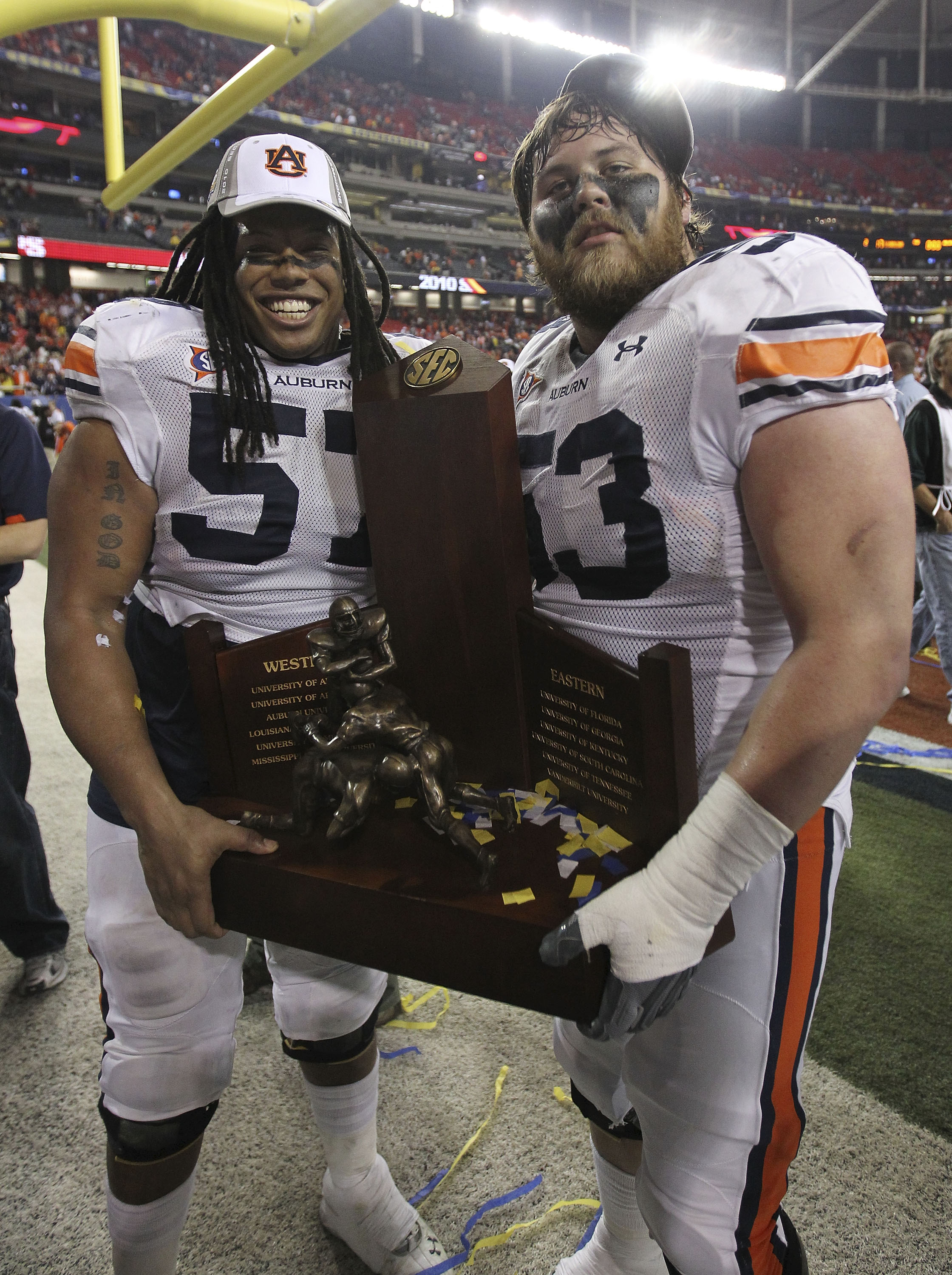 ATLANTA - DECEMBER 4:  Lineman Bryon Isom #57 (left) and Bart Eddins #53 of the Auburn Tigers celebrate with the SEC Championship trophy after the 2010 SEC Championship against the South Carolina Gamecocks at Georgia Dome on December 4, 2010 in Atlanta, G