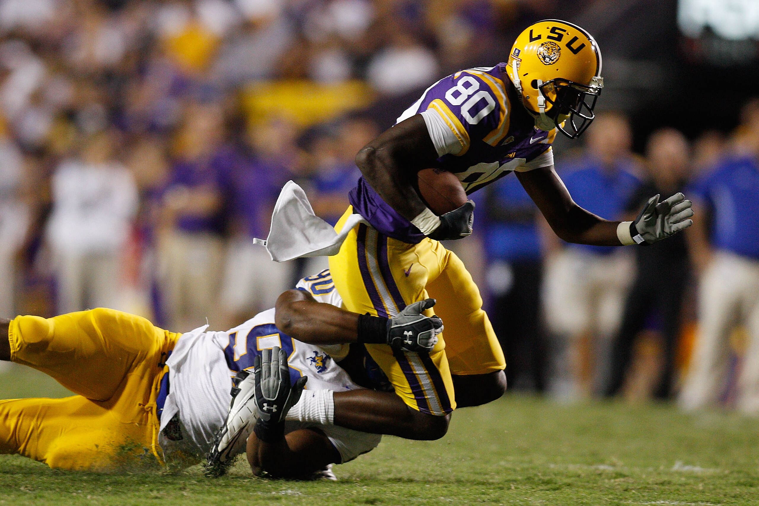 BATON ROUGE, LA - OCTOBER 16:   Terrence Toliver #80 of the Louisiana State University Tigers is tackled by Pat Williams #90 of the McNeese State Cowboys at Tiger Stadium on October 16, 2010 in Baton Rouge, Louisiana.  The Tigers defeated the Cowboys 32-1