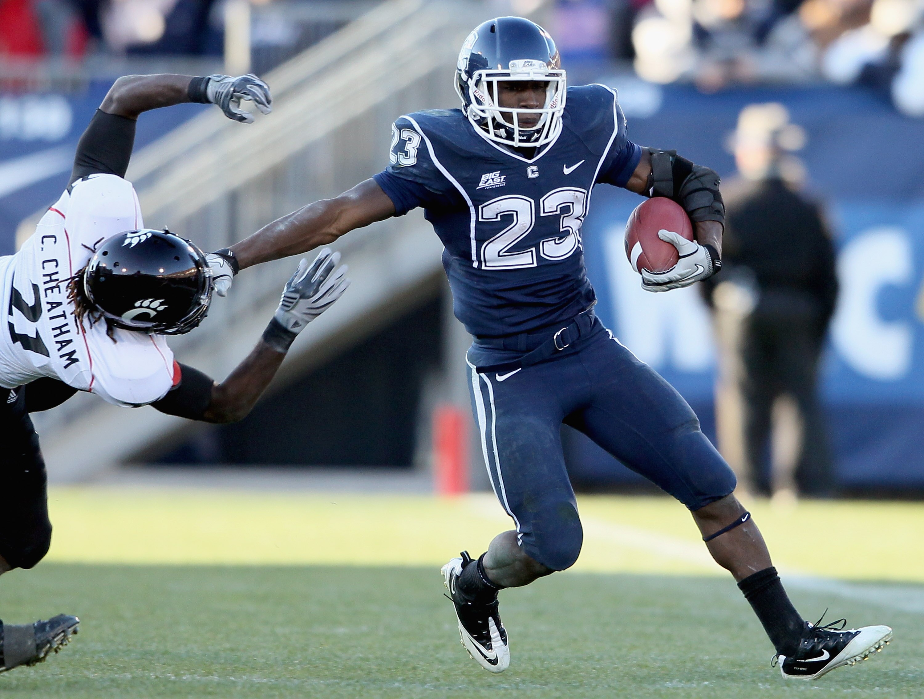 EAST HARTFORD, CT - NOVEMBER 27:  Jordan Todman #23 of the Connecticut Huskies carries the ball as Camerron Cheatham #21 of the Cincinnati Bearcats defends on November 27, 2010 at Rentschler Field in East Hartford, Connecticut. The Huskies defeated the Be