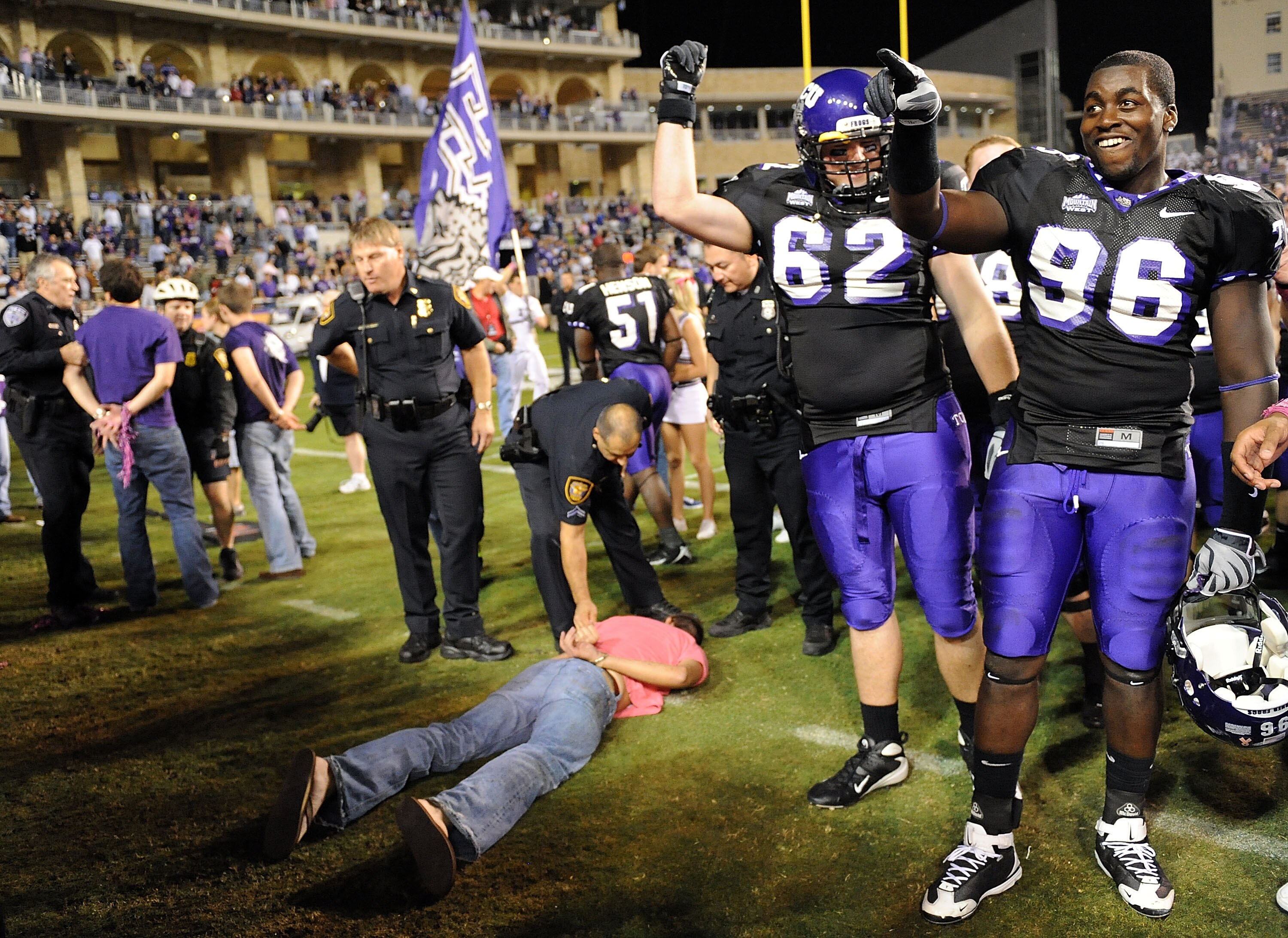 FORT WORTH, TX - OCTOBER 16:  Defensive end Wayne Daniels #96 and Jeff Olson #62 of the TCU Horned Frogs celebrate a win against the BYU Cougars as fans are detained by Fort Worth Police at Amon G. Carter Stadium on October 16, 2008 in Fort Worth, Texas.