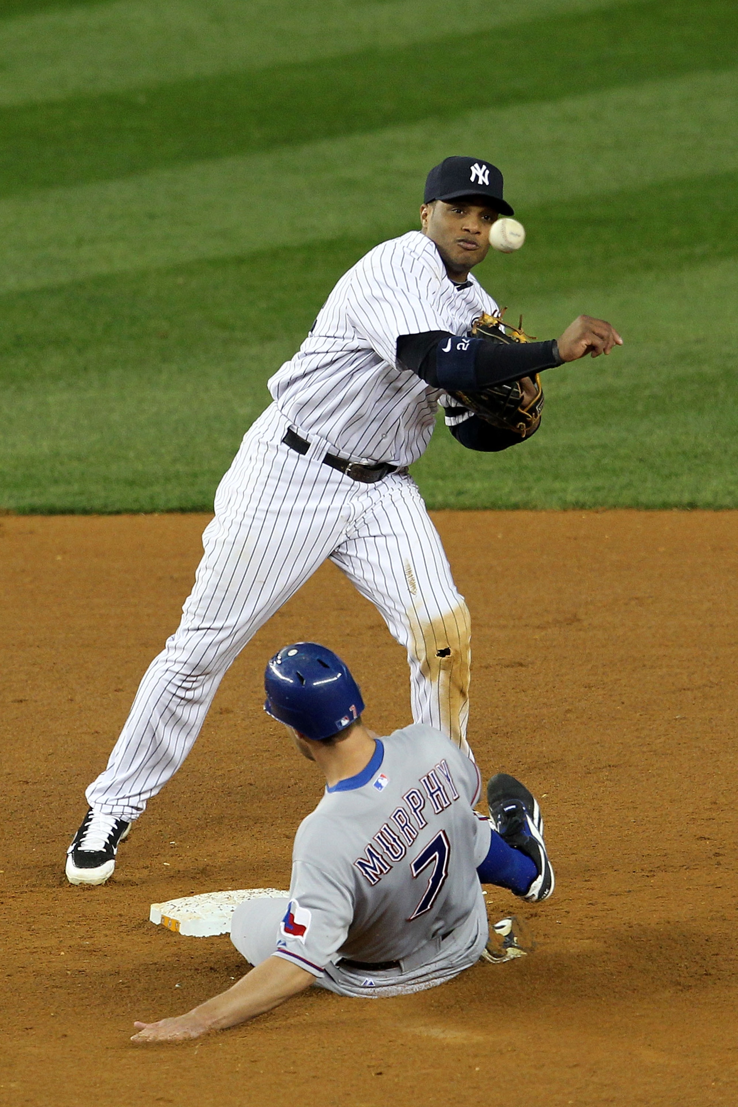 NEW YORK - OCTOBER 19:  Robinson Cano #24 of the New York Yankees turns a successful double play in the ninth inning over a sliding David Murphy #7 of the Texas Rangers in Game Four of the ALCS during the 2010 MLB Playoffs at Yankee Stadium on October 19,
