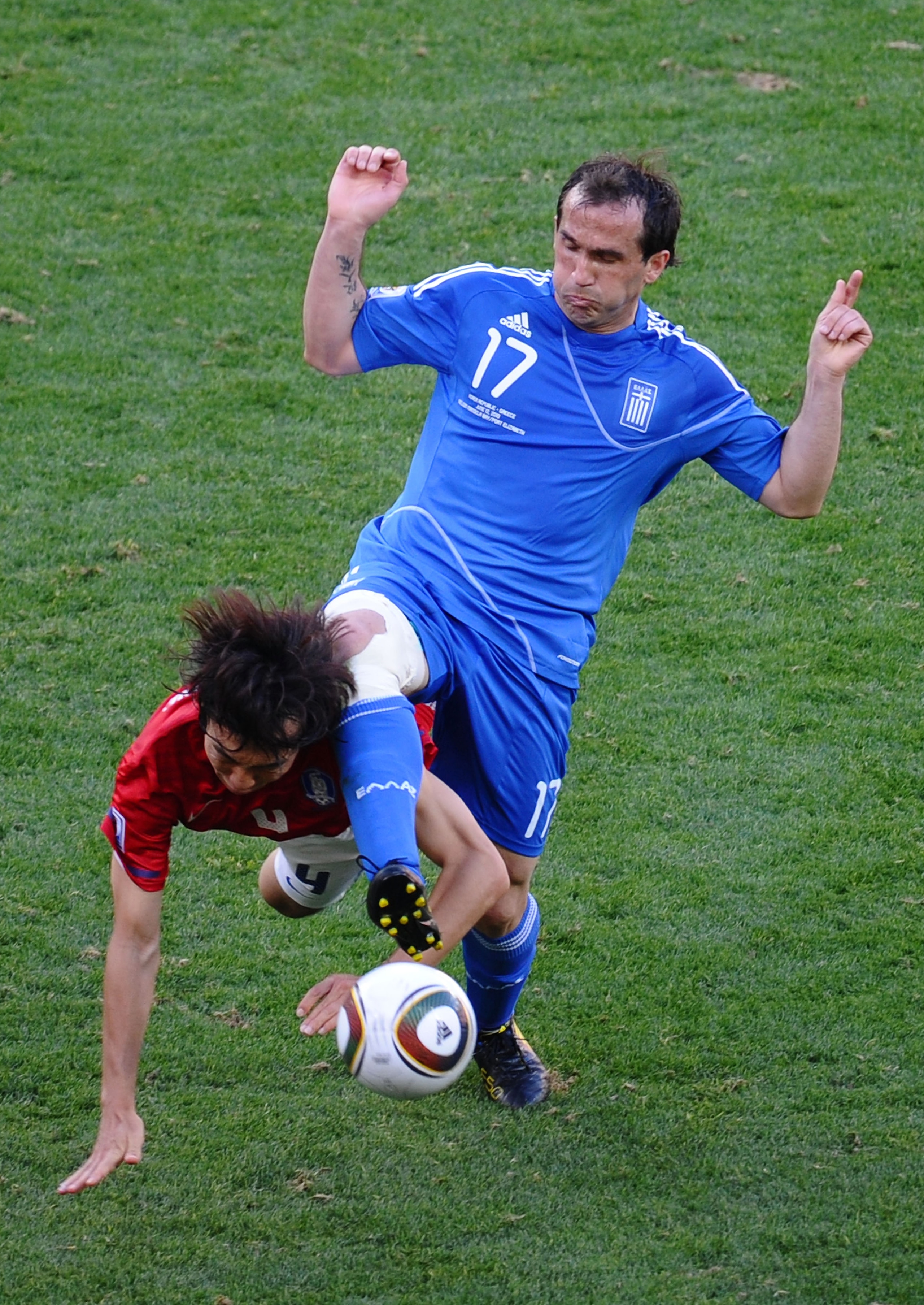 PORT ELIZABETH, SOUTH AFRICA - JUNE 12:  Cho Yong-Hyung of South Korea is tackled by Theofanis Gekas of Greece during the 2010 FIFA World Cup South Africa Group B match between South Korea and Greece at Nelson Mandela Bay Stadium on June 12, 2010 in Port