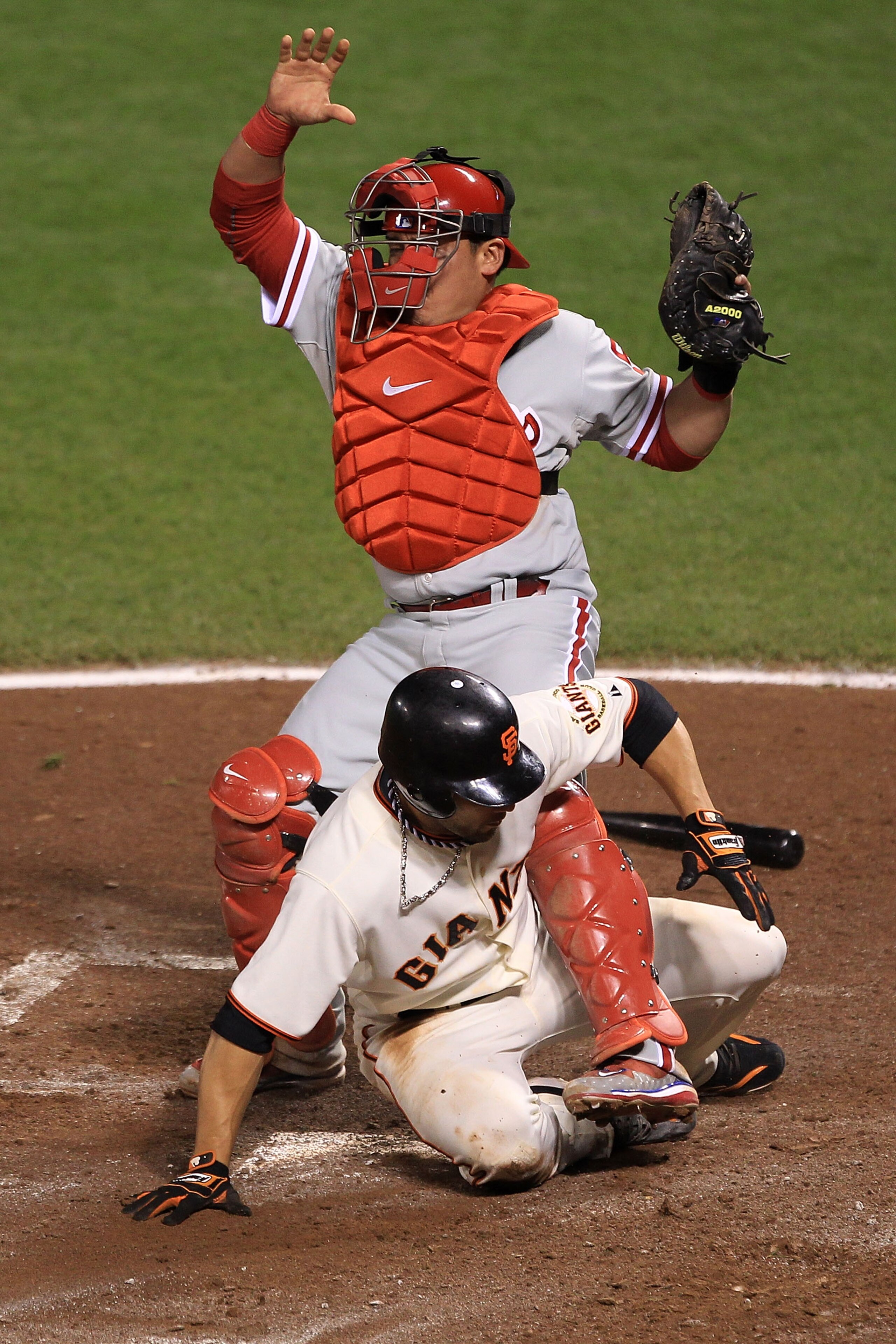 SAN FRANCISCO - OCTOBER 20:  Andres Torres #56 of the San Francisco Giants slides safely under the legs of Carlos Ruiz #51 of the Philadelphia Phillies to score a run in the in the fifth inning off a Aubrey Huff #17 RBI single in Game Four of the NLCS dur