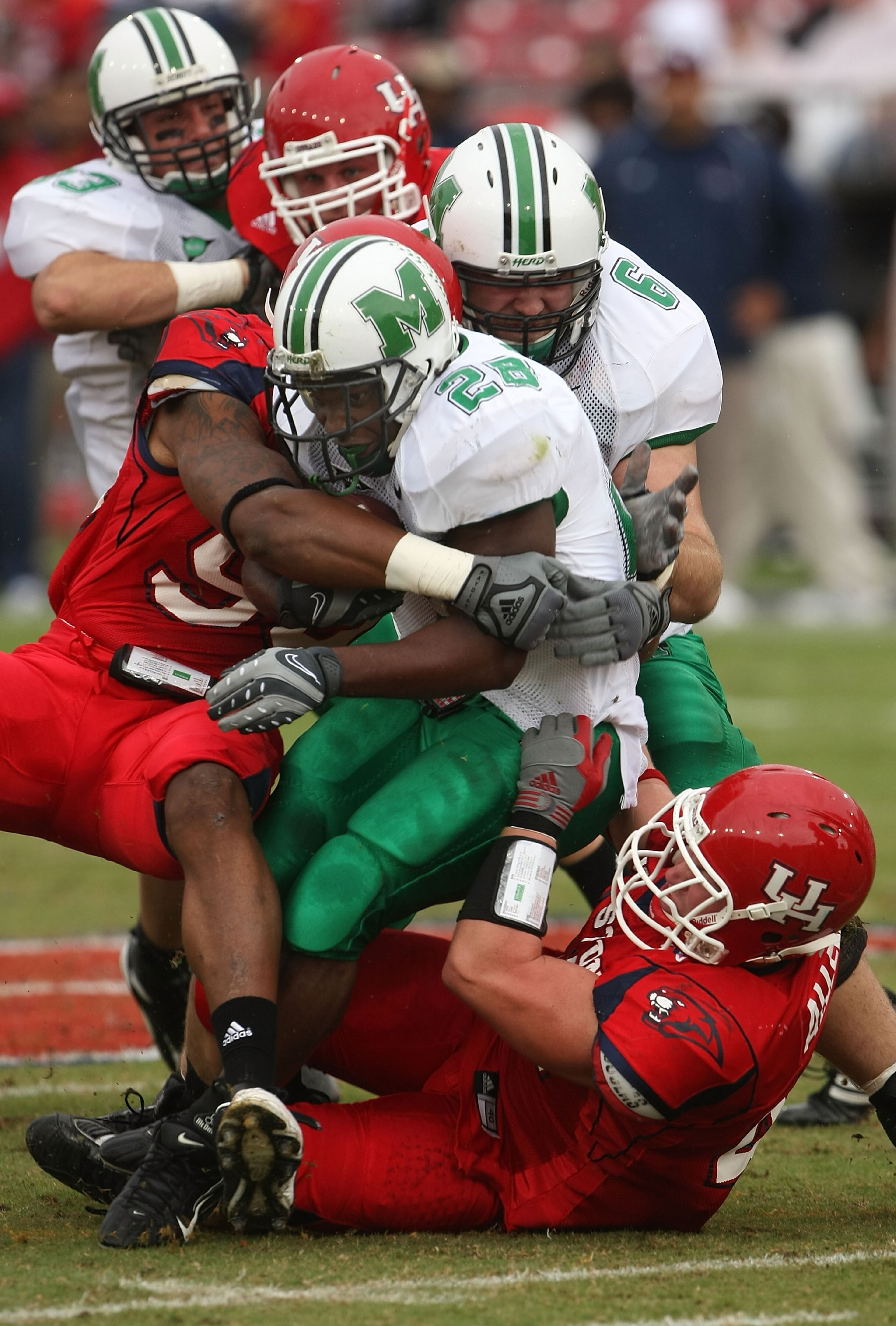 HOUSTON - NOVEMBER 17:  Running back Chubb Small #28 of the Marshall Thundering Herd is tackled by defensive lineman Ell Ash #90 and linebacker Trent Allen #41 of the Houston Cougars at Robertson Stadium November 17, 2007 in Houston, Texas. Houston won 35