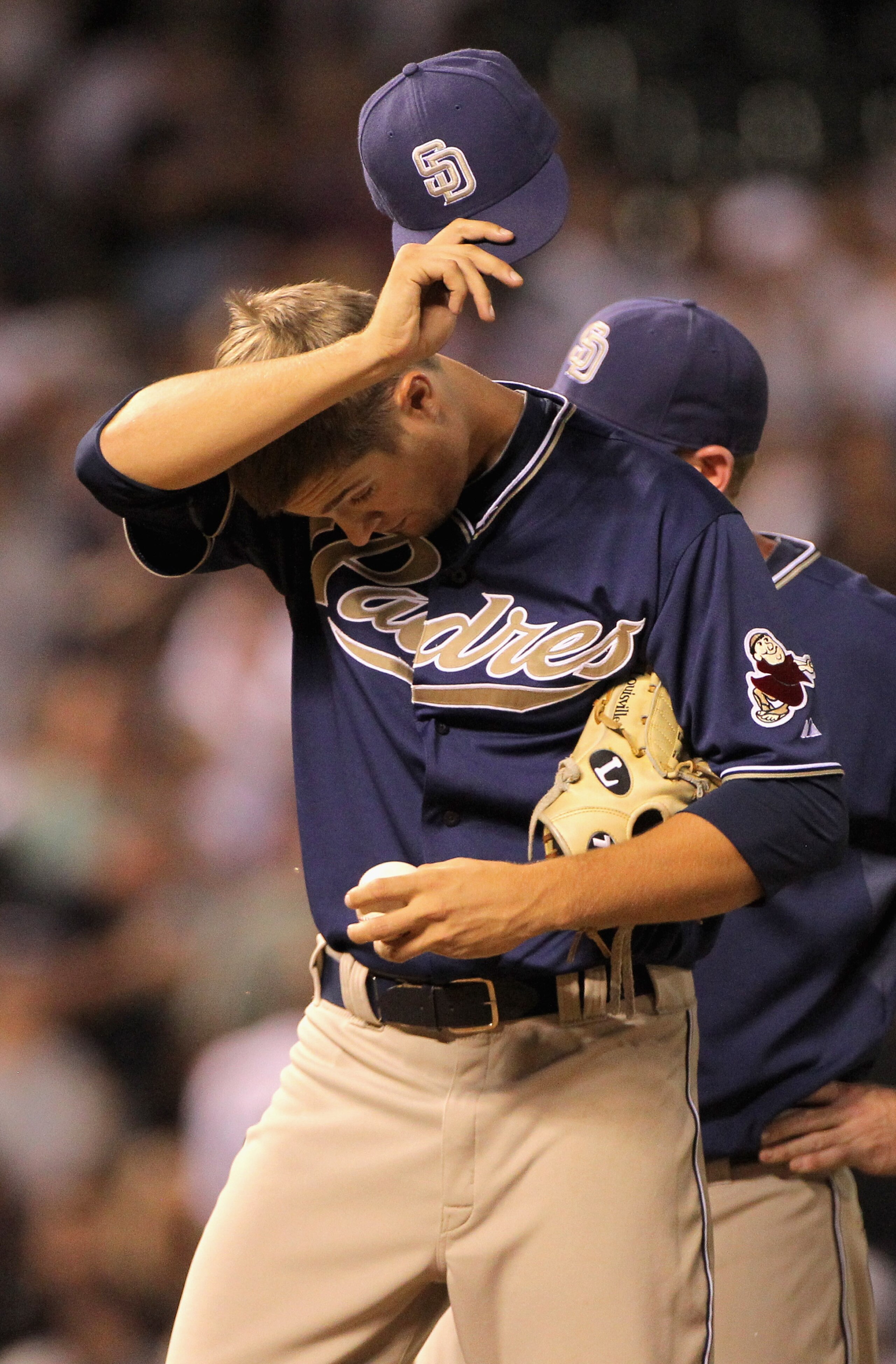DENVER - SEPTEMBER 13:  Starting pitcher Cory Luebke #50 of the San Diego Padres pauses as manager Bud Black heads to the mound to remove him from the game in the fifth inning against the Colorado Rockies at Coors Field on September 13, 2010 in Denver, Co