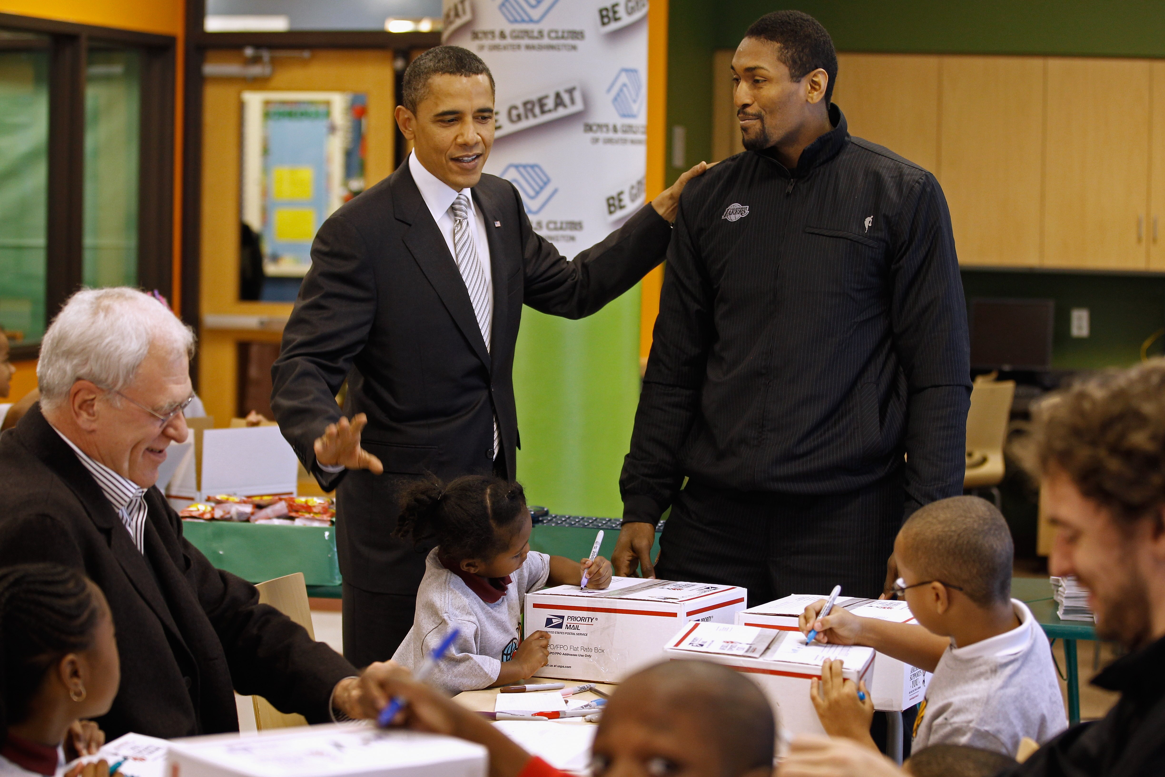WASHINGTON, DC - DECEMBER 13:  (AFP OUT) U.S. President Barack Obama (C) greets Los Angeles Lakers forward Ron Artest (R) and head coach Phil Jackson (L) while helping children volunteers fill care packages during a NBA Cares service event at the Boys and