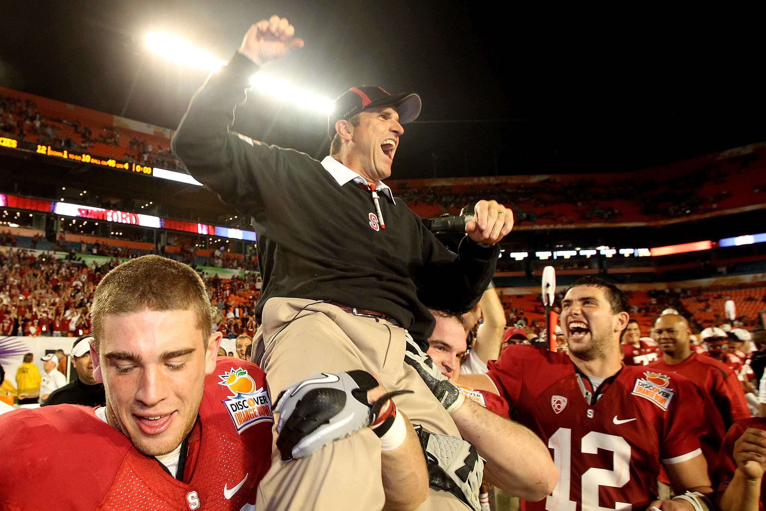 MIAMI, FL - JANUARY 03: Head coach Jim Harbaugh of the Stanford Cardinal celebrates as he is lifted up by his players including Orange Bowl MVP Andrew Luck #12 (R) after Stanford won 40-12 against the Virginia Tech Hokies during the 2011 Discover Orange B