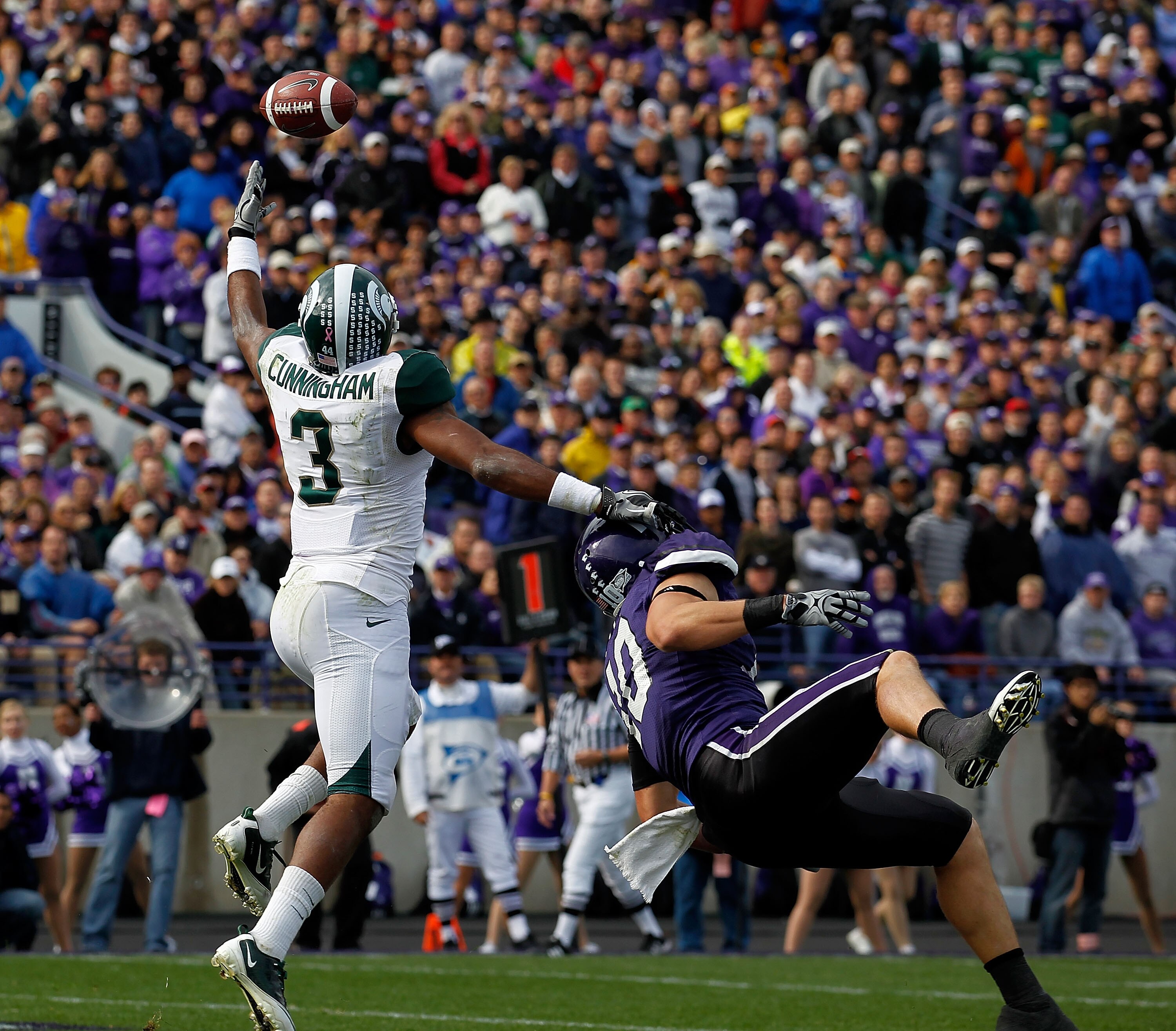EVANSTON, IL - OCTOBER 23: B.J. Cunningham #3 of the Michigan State Spartans leaps for the ball for a touchdown catch over Brian Peters #10 of the Northwestern Wildcats at Ryan Field on October 23, 2010 in Evanston, Illinois. Michigan State defeated North