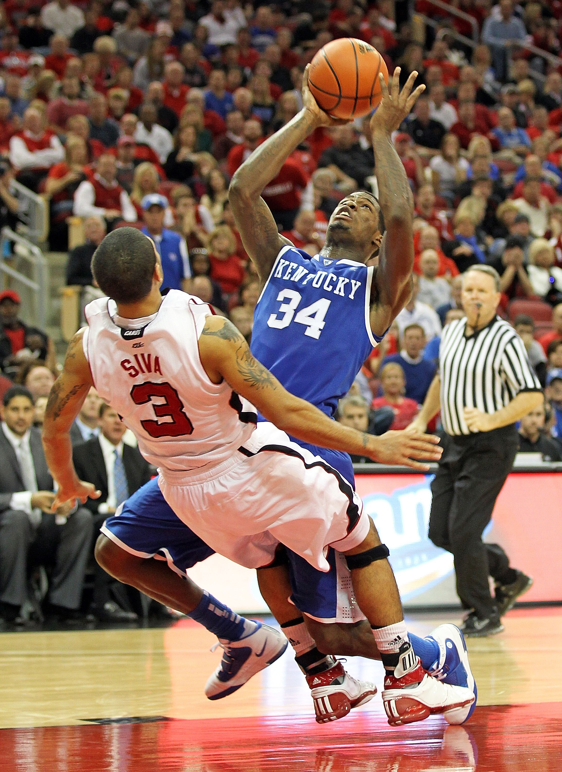 LOUISVILLE, KY - DECEMBER 31:  DeAndre Liggins #34 of the Kentucky Wildcats and Peyton Siva #3 of the Louisville Cardinals get tangled up during the game at the KFC Yum! Center on December 31, 2010 in Louisville, Kentucky. Kentucky won 78-63.  (Photo by A