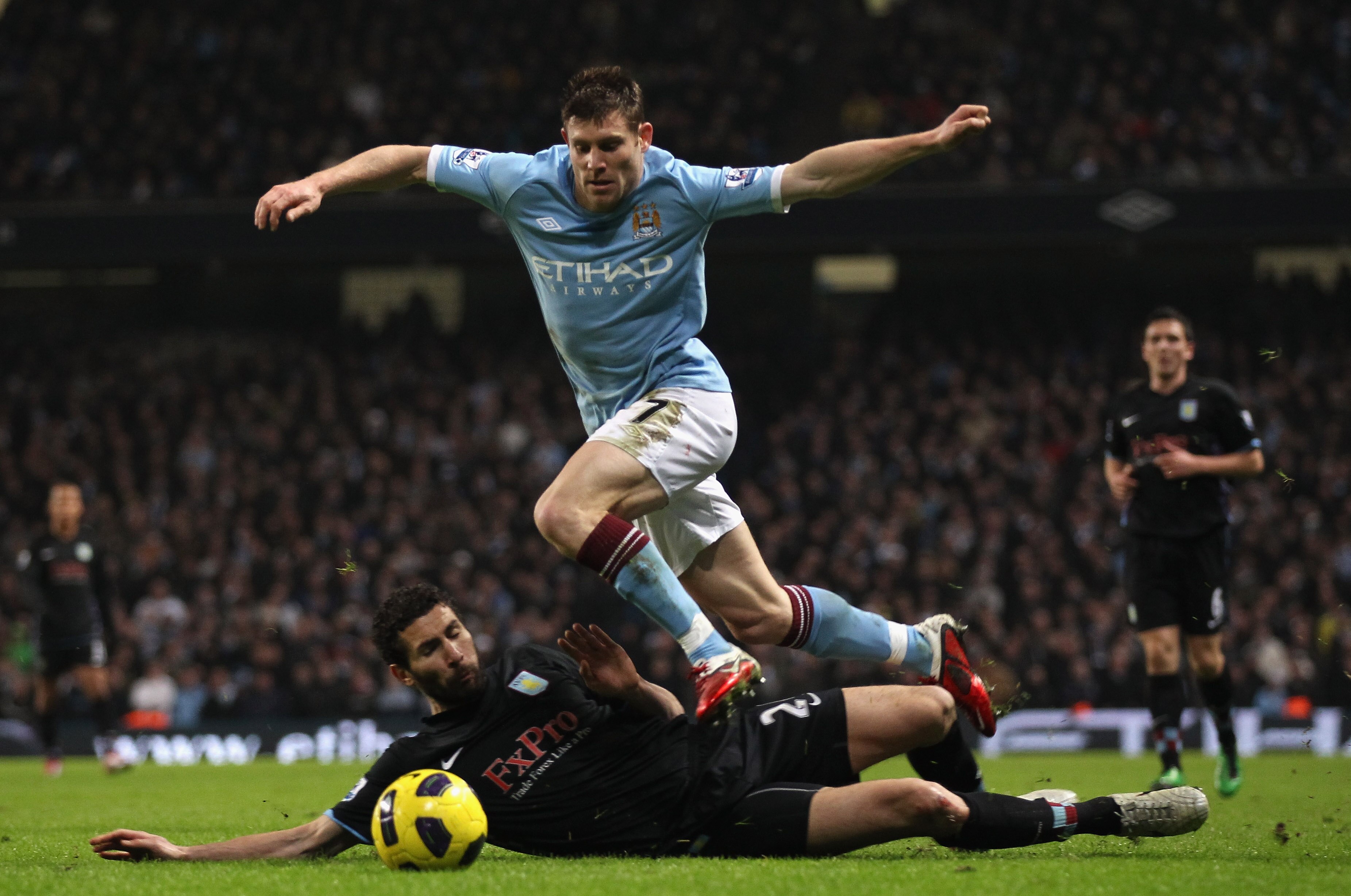 MANCHESTER, ENGLAND - DECEMBER 28:  James Milner of Manchester City beats a challenge from Carlos Cuellar of Aston Villa during the Barclays Premier League match between Manchester City and Aston Villa at the City of Manchester Stadium on December 28, 201