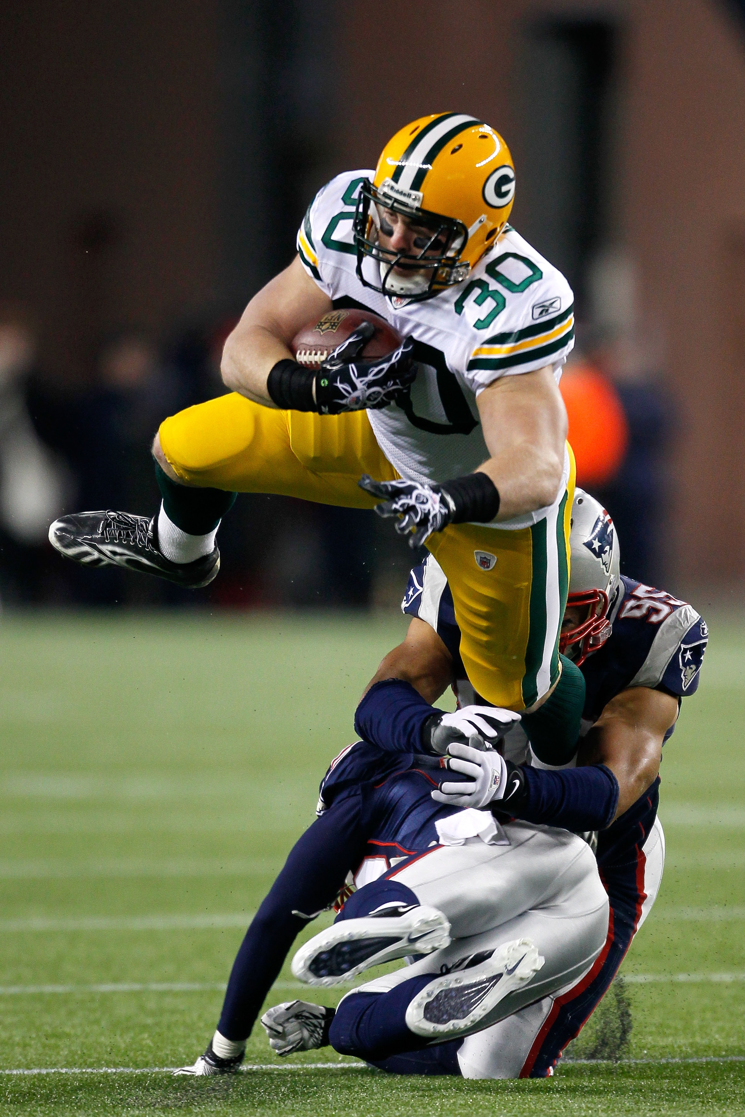 FOXBORO, MA - DECEMBER 19:  Running back John Kuhn #30 of the Green Bay Packers is tackled by linebacker Tully Banta-Cain #95 and cornerback Devin McCourty #32 of the New England Patriots during the first quarter of the game at Gillette Stadium on Decembe