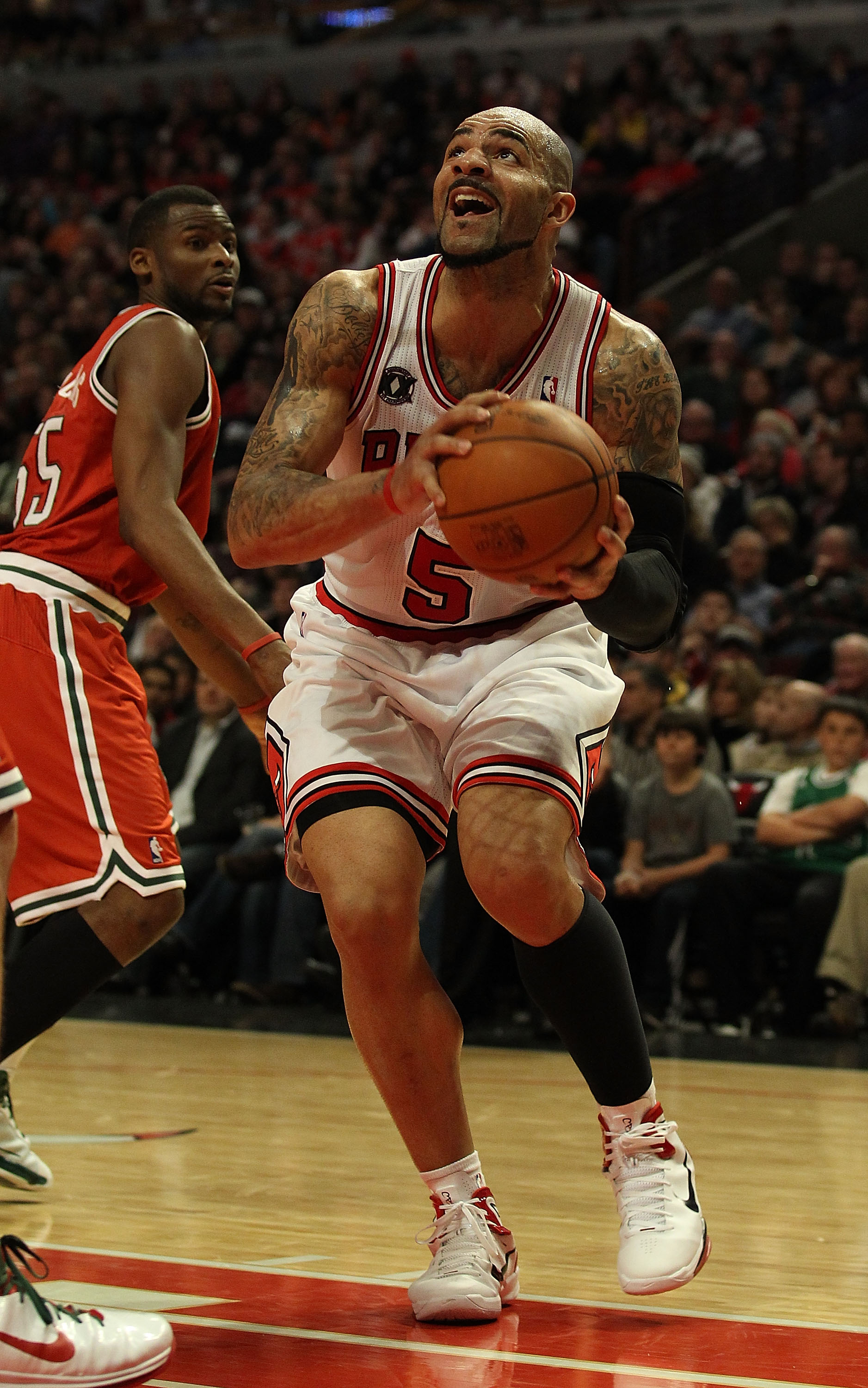 CHICAGO, IL - DECEMBER 28: Carlos Boozer #5 of the Chicago Bulls goes up for a shot past Keyon Dooling #55 of the Milwaukee Bucks at the United Center on December 28, 2010 in Chicago, Illinois. The Bulls defeated the Bucks 90-77. NOTE TO USER: User expres