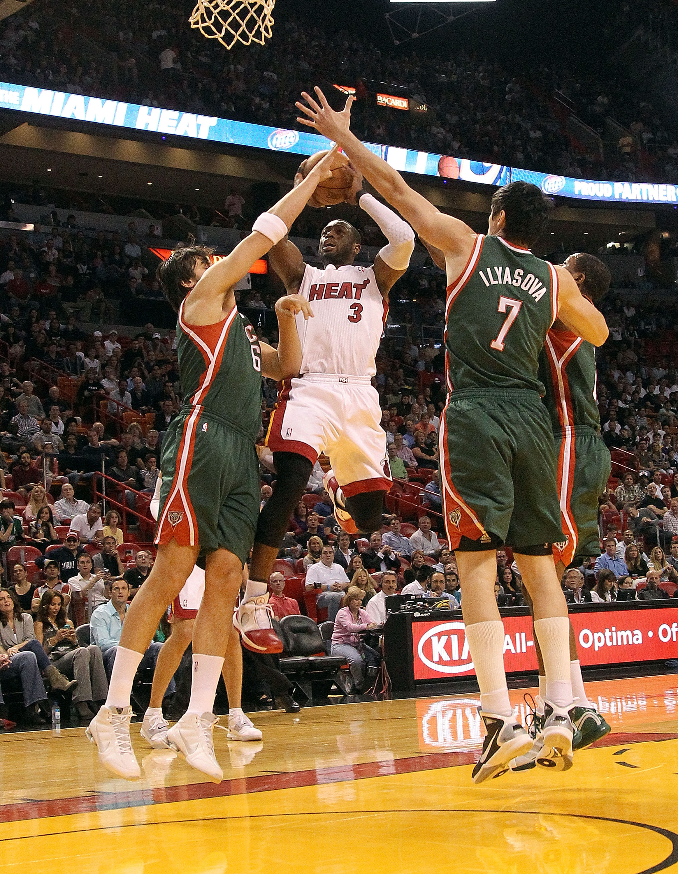 MIAMI, FL - JANUARY 04:  Dwyane Wade #3 of the Miami Heat shoots over  Andrew Bogut #6 and Ersan Ilyasova #7 of the Milwaukee Bucks during a game at American Airlines Arena on January 4, 2011 in Miami, Florida. NOTE TO USER: User expressly acknowledges an