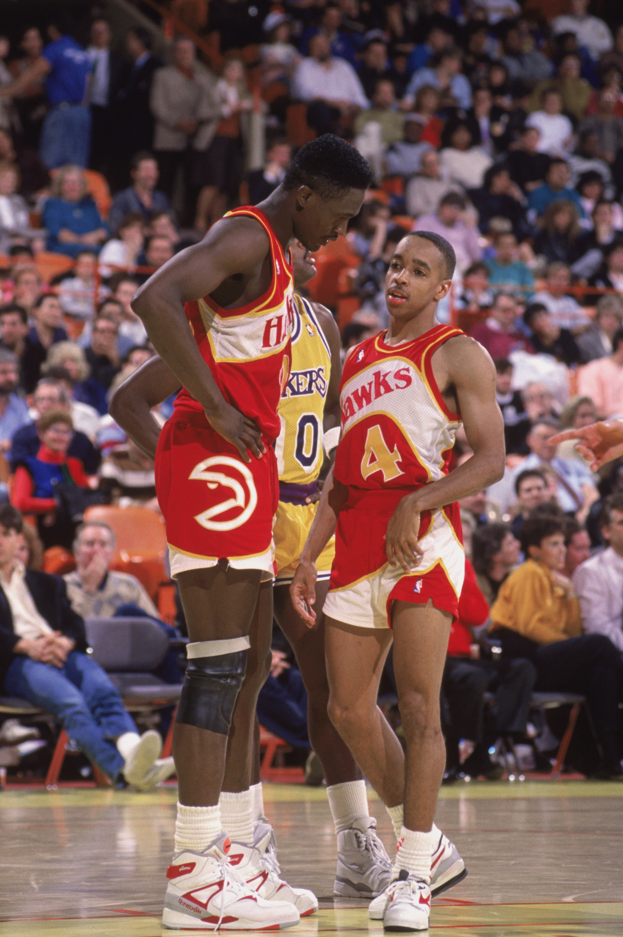 INGLEWOOD, CA - 1989:  Spud Webb #4 of the Atlanta Hawks listens to teammate Dominique Wilkins #21 during a NBA game against the Los Angeles Lakers at the Great Western Forum in Inglewood, California in 1989.  (Photo by Ken Levine/Getty Images)