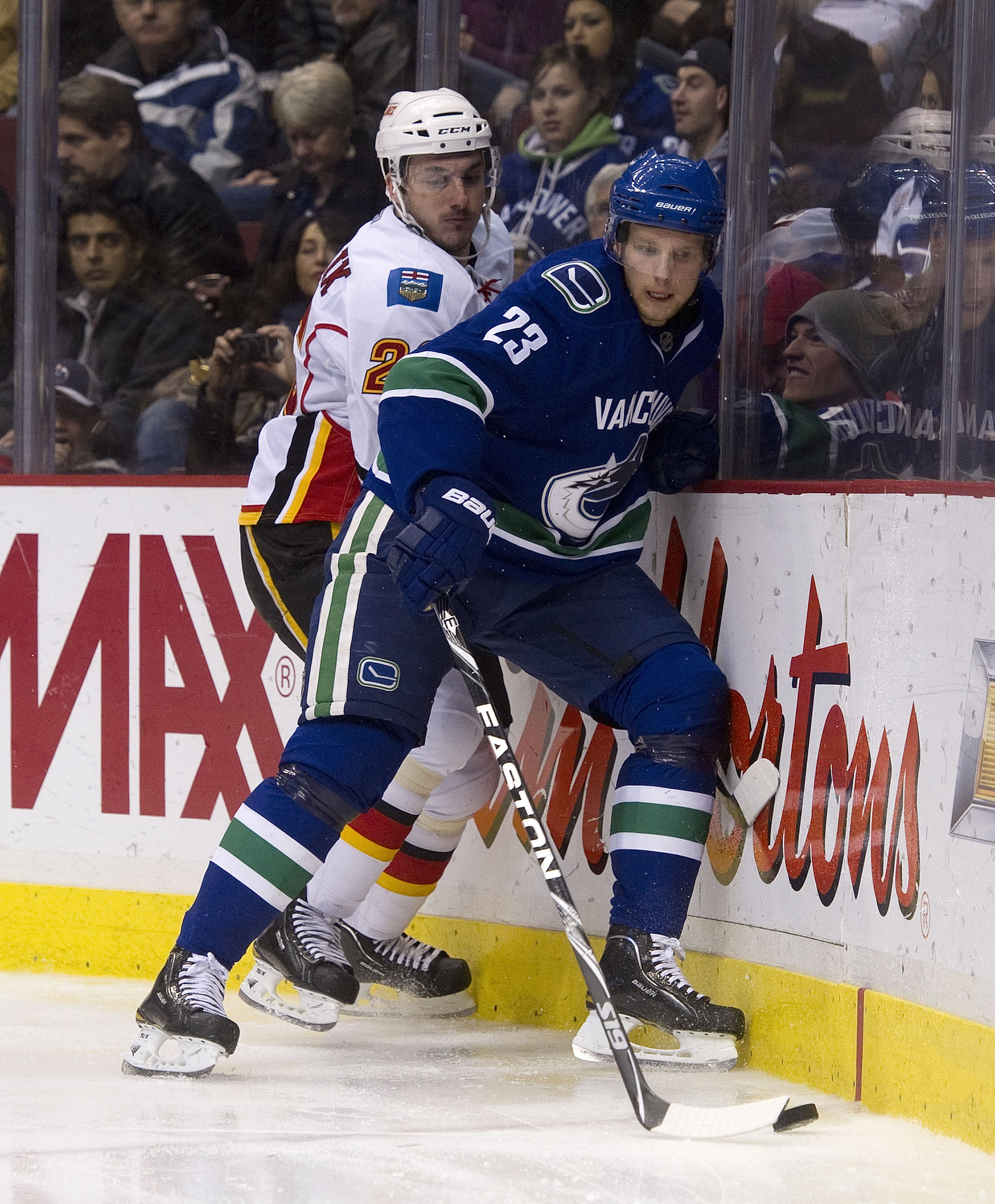 VANCOUVER, CANADA - JANUARY 5: Alexander Edler #23 of the Vancouver Canucks gains control of the loose puck while being checked by Ales Kotalik #26 of the Calgary Flames during the third period in NHL action on January 05, 2011 at Rogers Arena in Vancouve