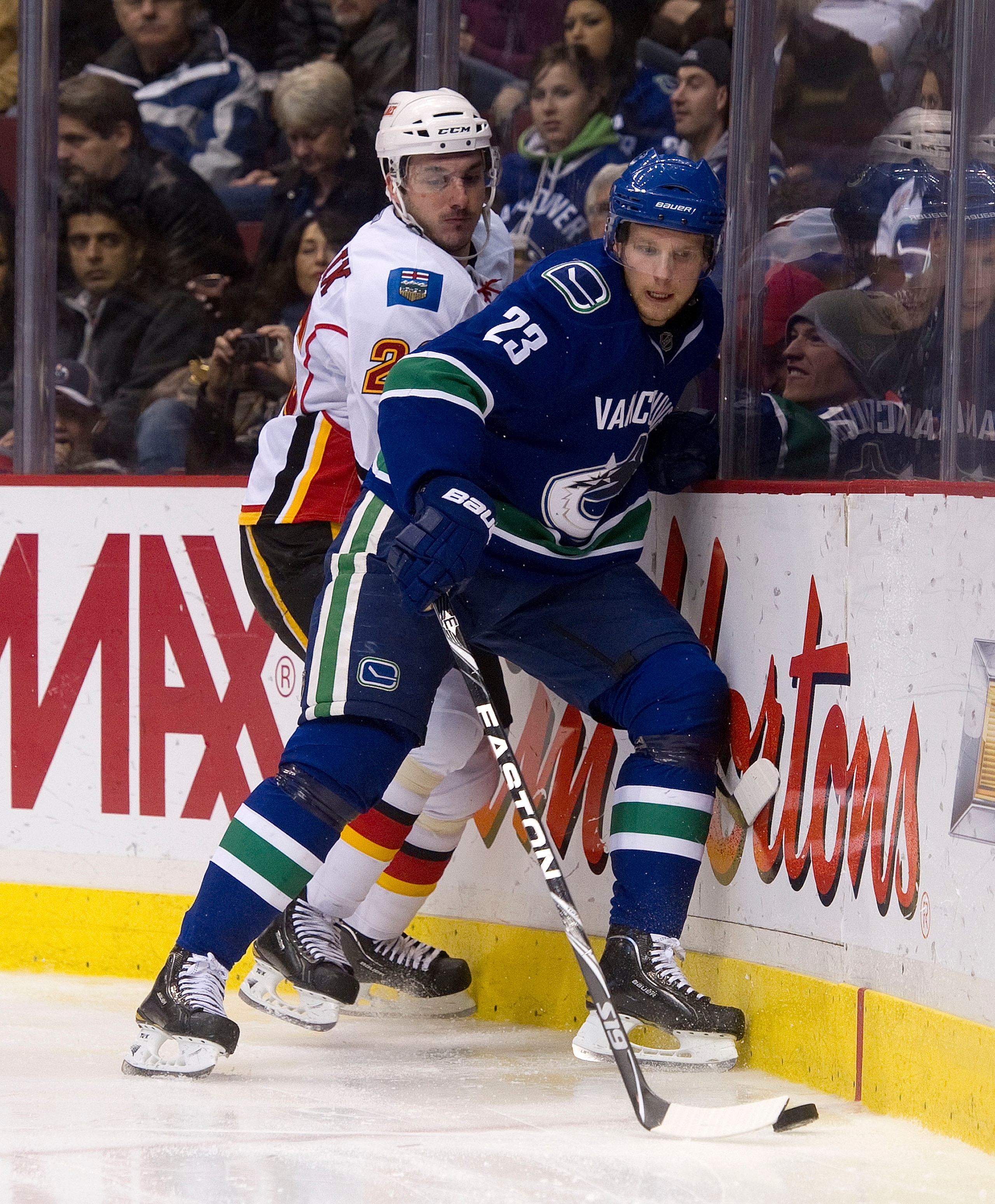 VANCOUVER, CANADA - JANUARY 5: Alexander Edler #23 of the Vancouver Canucks gains control of the loose puck while being checked by Ales Kotalik #26 of the Calgary Flames during the third period in NHL action on January 05, 2011 at Rogers Arena in Vancouve VANCOUVER, CANADA - JANUARY 5: Alexander Edler #23 of the Vancouver Canucks gains control of the loose puck while being checked by Ales Kotalik #26 of the Calgary Flames during the third period in NHL action on January 05, 2011 at Rogers Arena in Vancouve