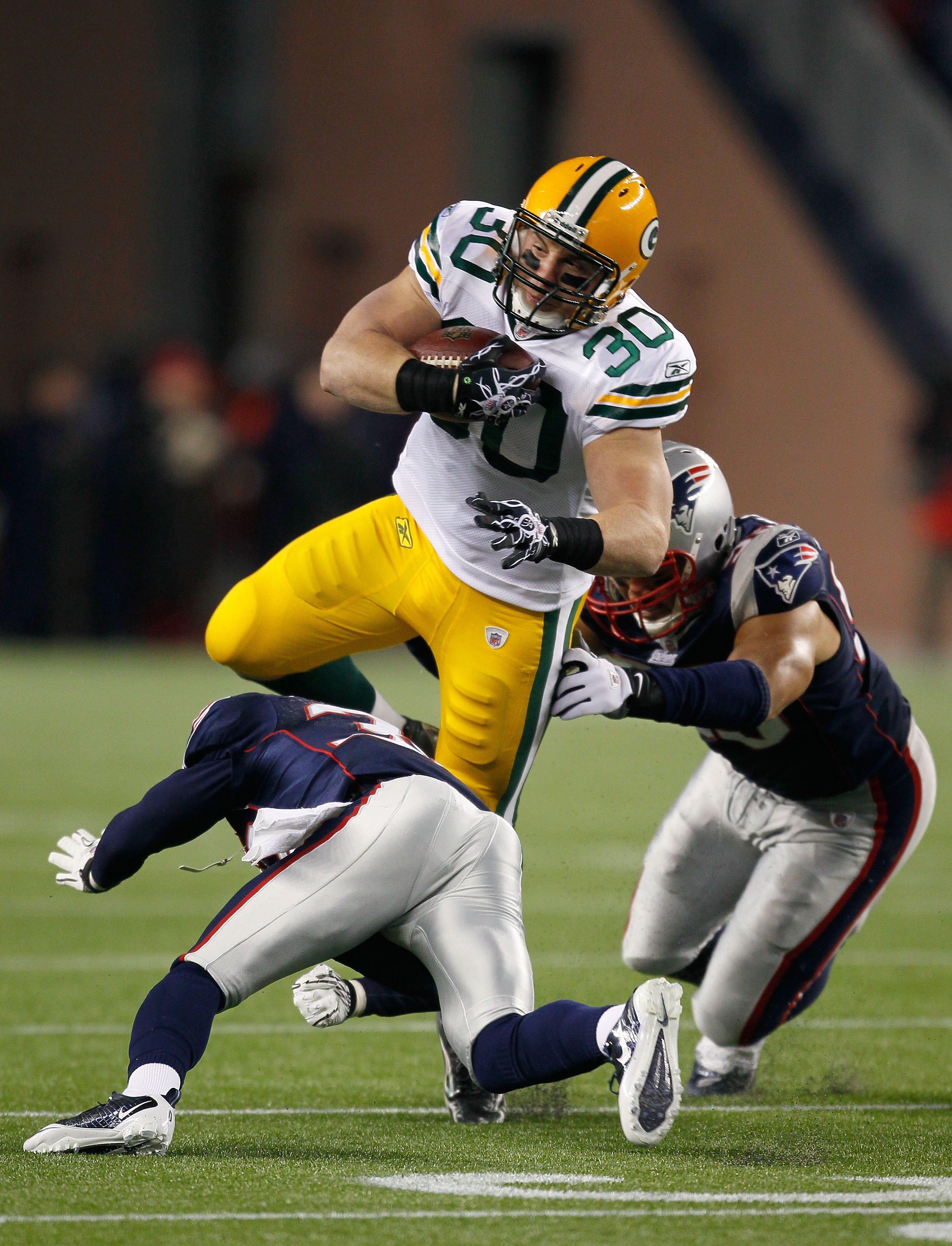 FOXBORO, MA - DECEMBER 19:  Running back John Kuhn #30 of the Green Bay Packers is tackled by linebacker Tully Banta-Cain #95 and cornerback Devin McCourty #32 of the New England Patriots during the first quarter of the game at Gillette Stadium on Decembe