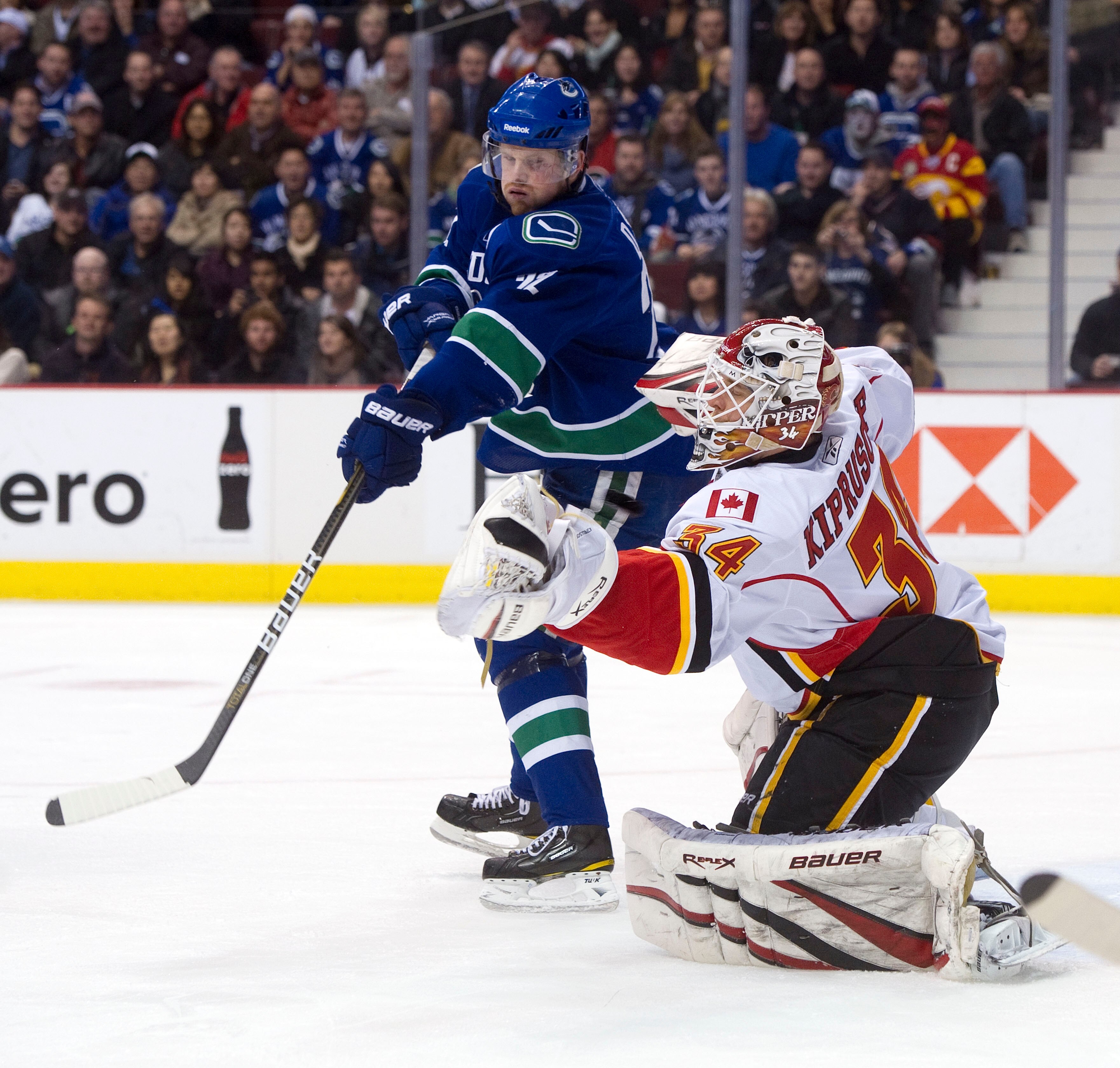 VANCOUVER, CANADA - JANUARY 5: Daniel Sedin #22 of the Vancouver Canucks deflects the puck past goalie Miikka Kiprusoff #34 of the Calgary Flames during the second period in NHL action on January 05, 2011 at Rogers Arena in Vancouver, BC, Canada.  (Photo