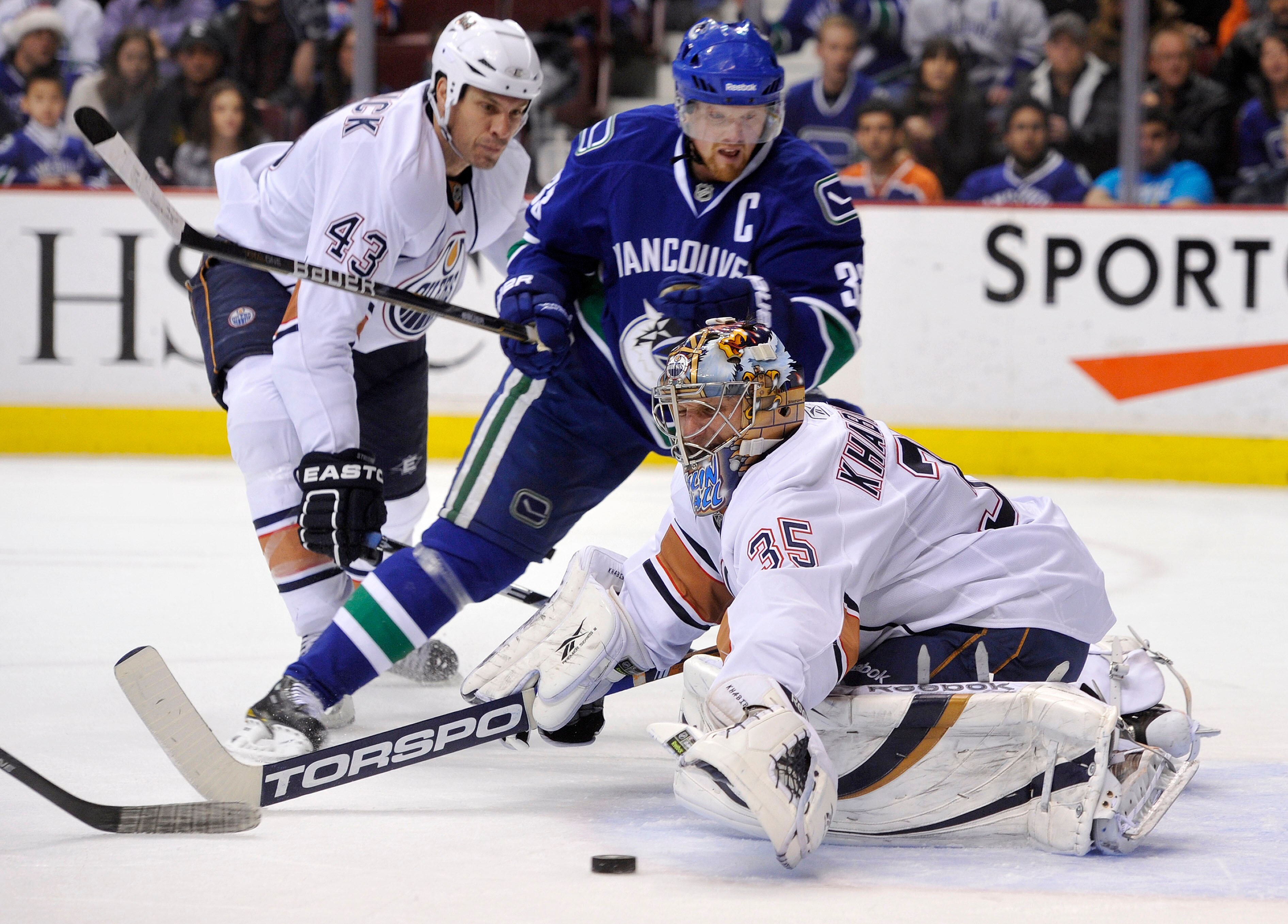 VANCOUVER, CANADA - DECEMBER 26: Goalie Nikolai Khabibulin #35 of the Edmonton Oilers tries to cover up the puck while Henrik Sedin #33 of the Vancouver Canucks crashes the net during the second period in NHL action on December 26, 2010 at Rogers Arena in