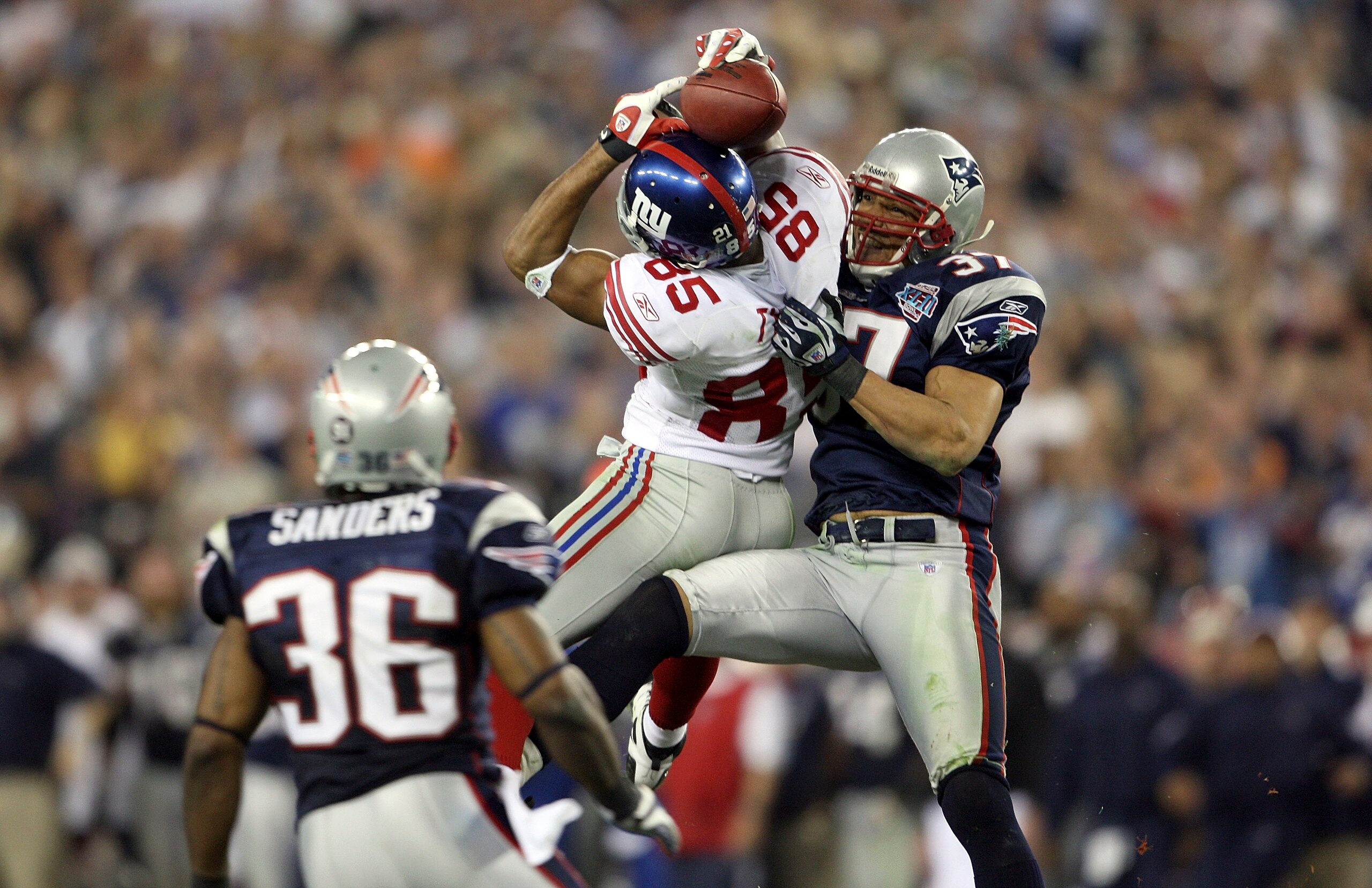 GLENDALE, AZ - FEBRUARY 03:  David Tyree #85 of the New York Giants catches a 32-yard pass from Eli Manning #10 against Rodney Harrison #37 and James Sanders #36 of the New England Patriots attempts to knock it out in the fourth quarter of Super Bowl XLII