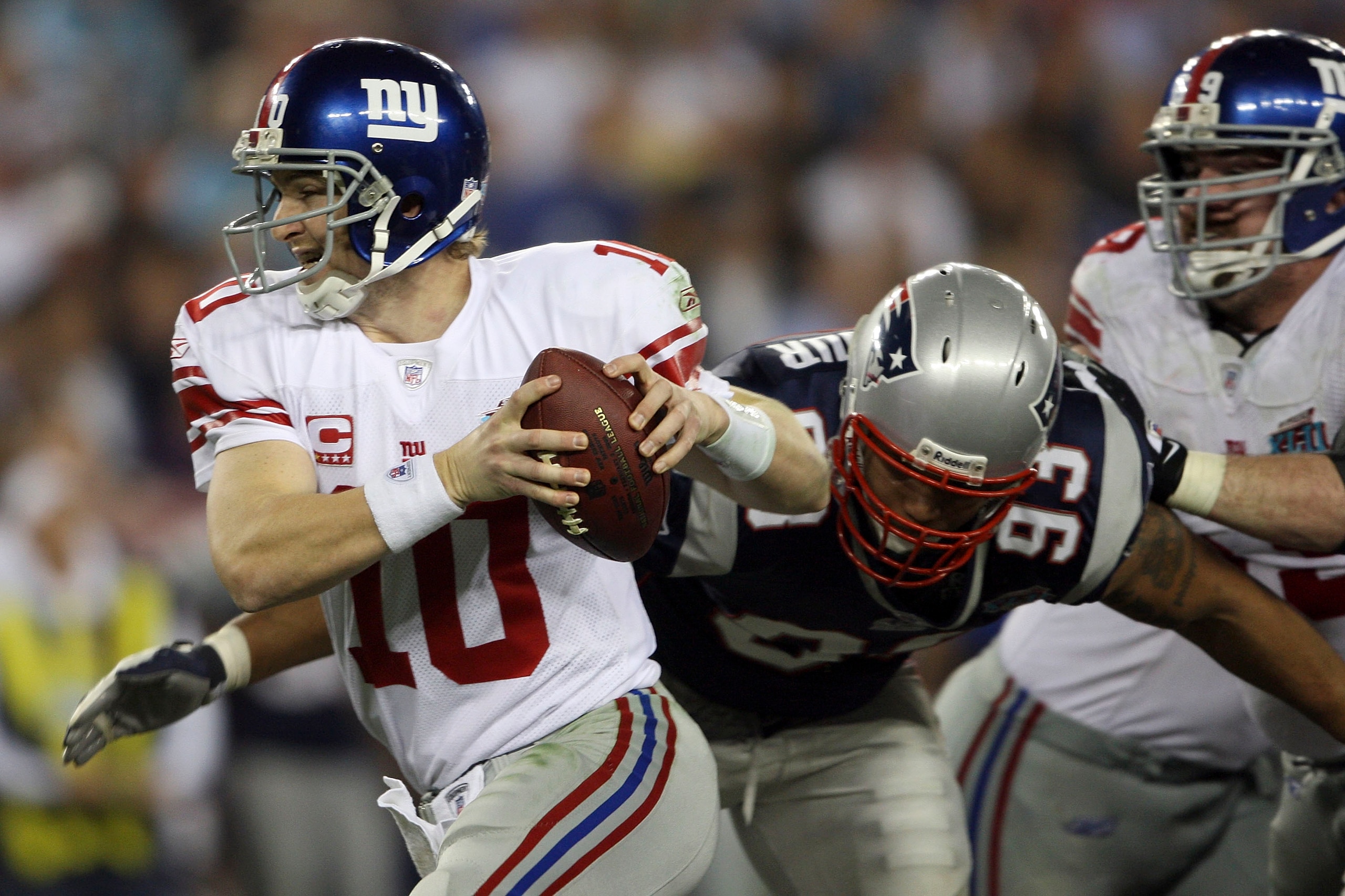 GLENDALE, AZ - FEBRUARY 03:  Quarterback Eli Manning #10 of the New York Giants avoids getting sacked by Richard Seymour #93 of the New England Patriots during the fourth quarter of Super Bowl XLII on February 3, 2008 at the University of Phoenix Stadium